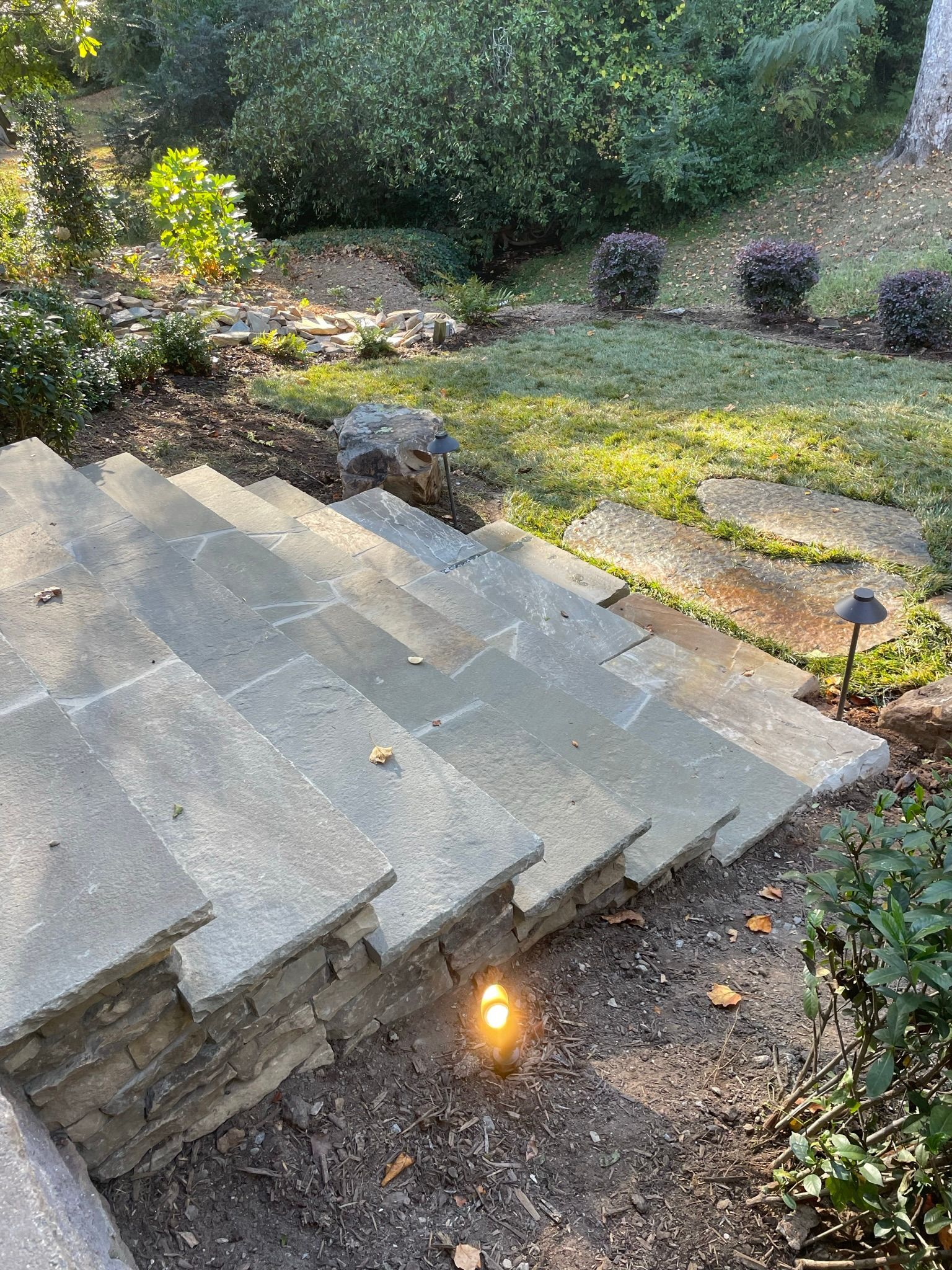 A set of stone stairs leading up to a lush green yard.