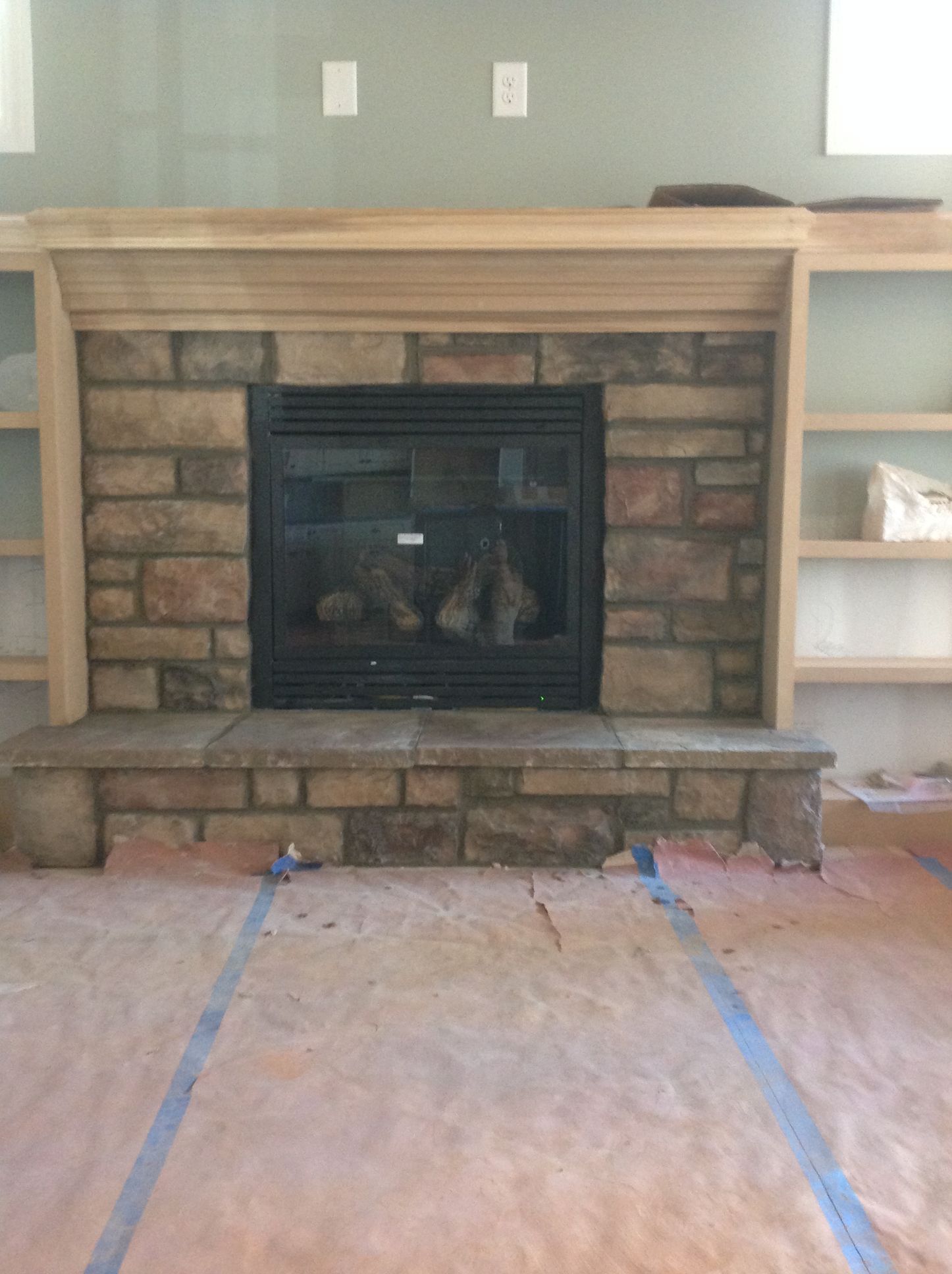 A brick fireplace with a wooden mantle in a living room