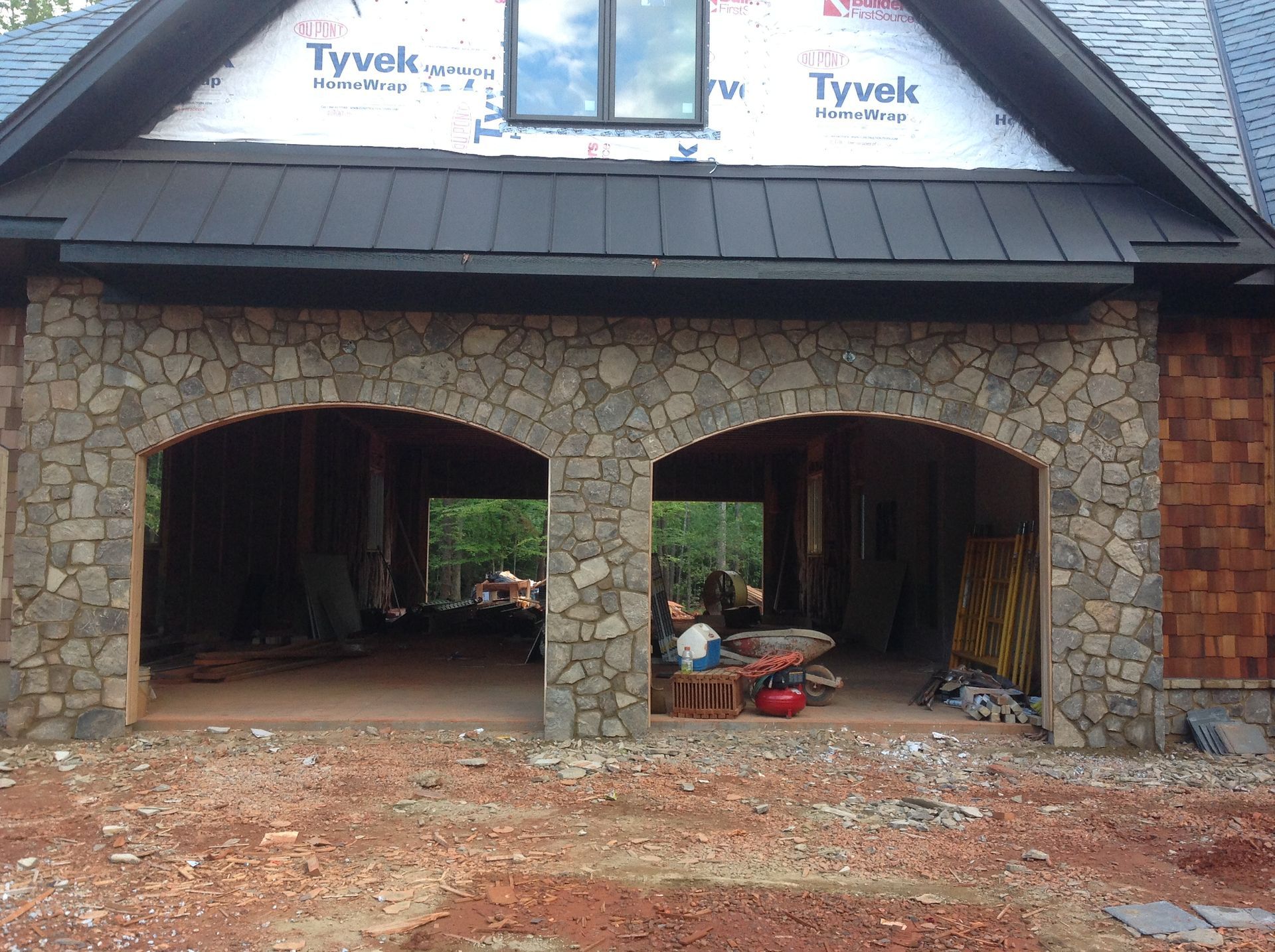 A house is being built with a black roof and stone arches.