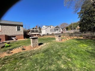 A backyard with a fence and a house in the background.