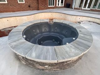 A round hot tub is sitting in the middle of a concrete patio.