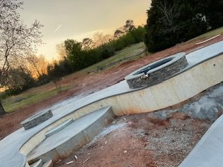 A concrete patio with a fire pit in the middle of it.