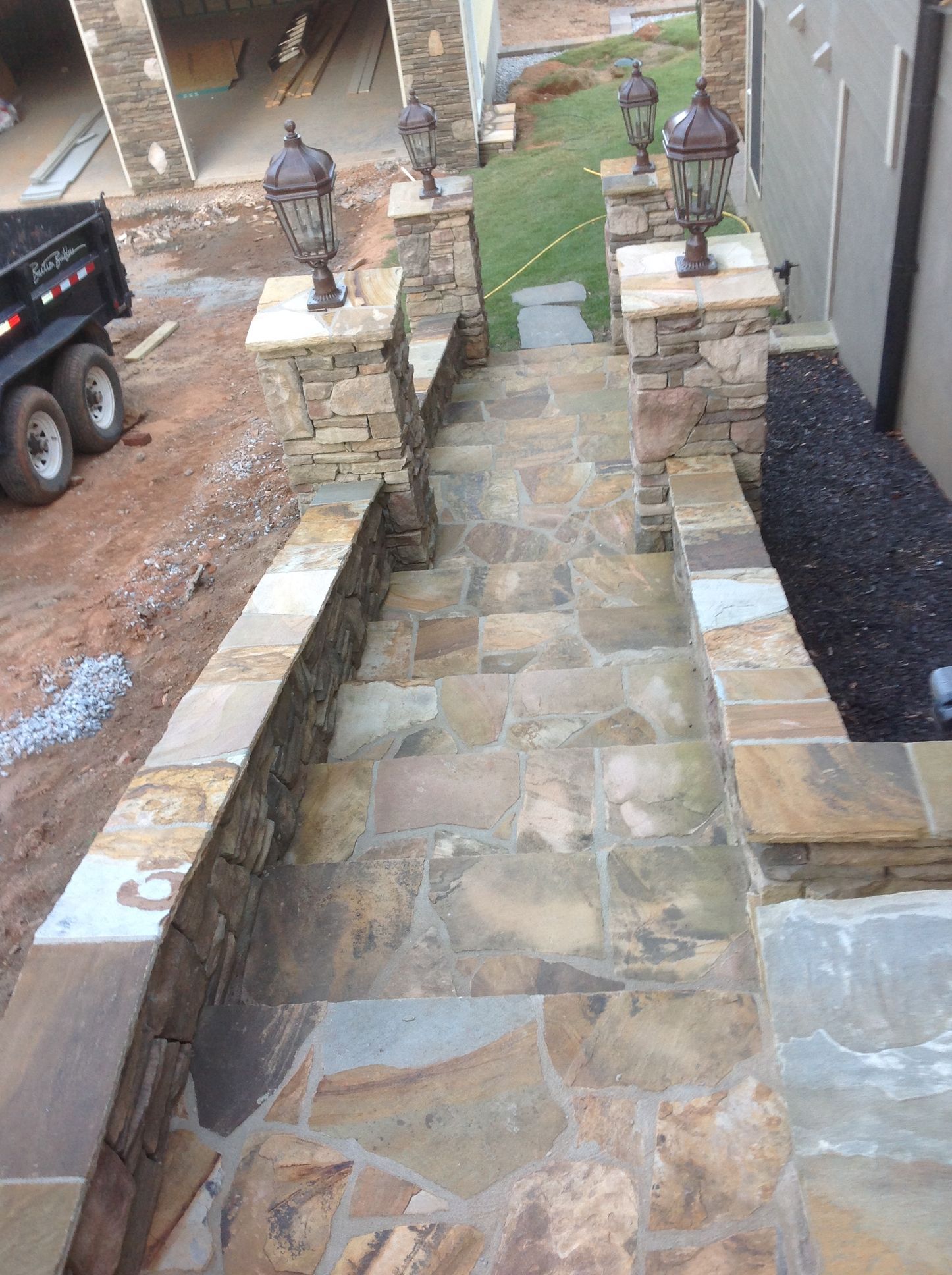 A stone staircase leading up to a house with a dumpster in the background.