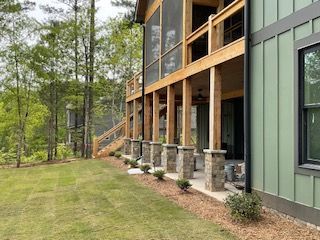 A large house with a screened in porch and a large lawn in front of it.