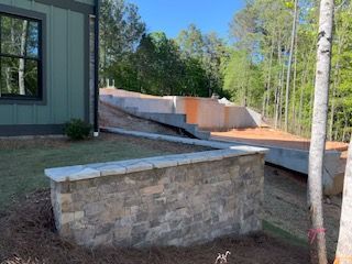 A stone wall is being built in front of a house.