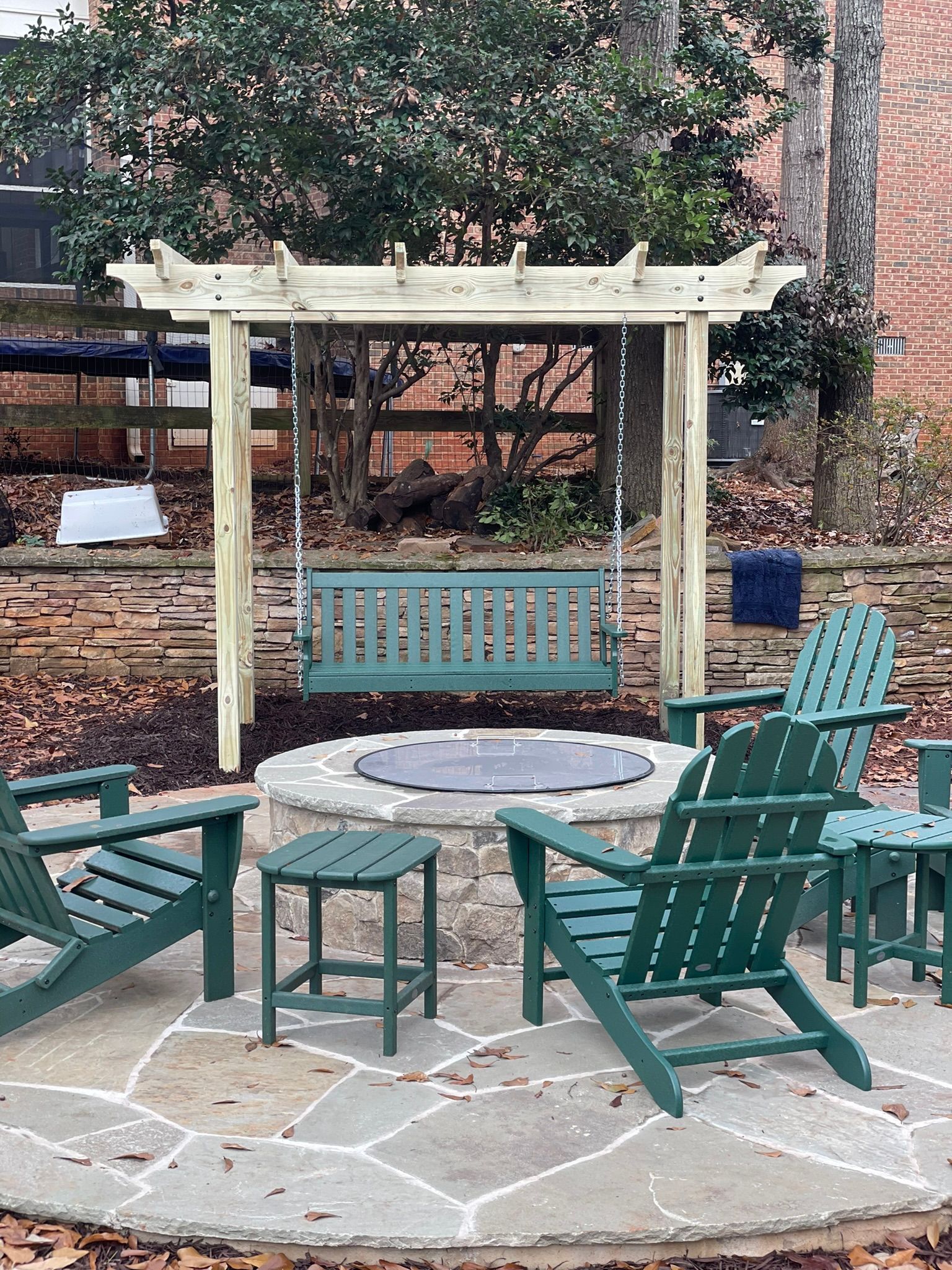 There is a fire pit with a swing and chairs around it.