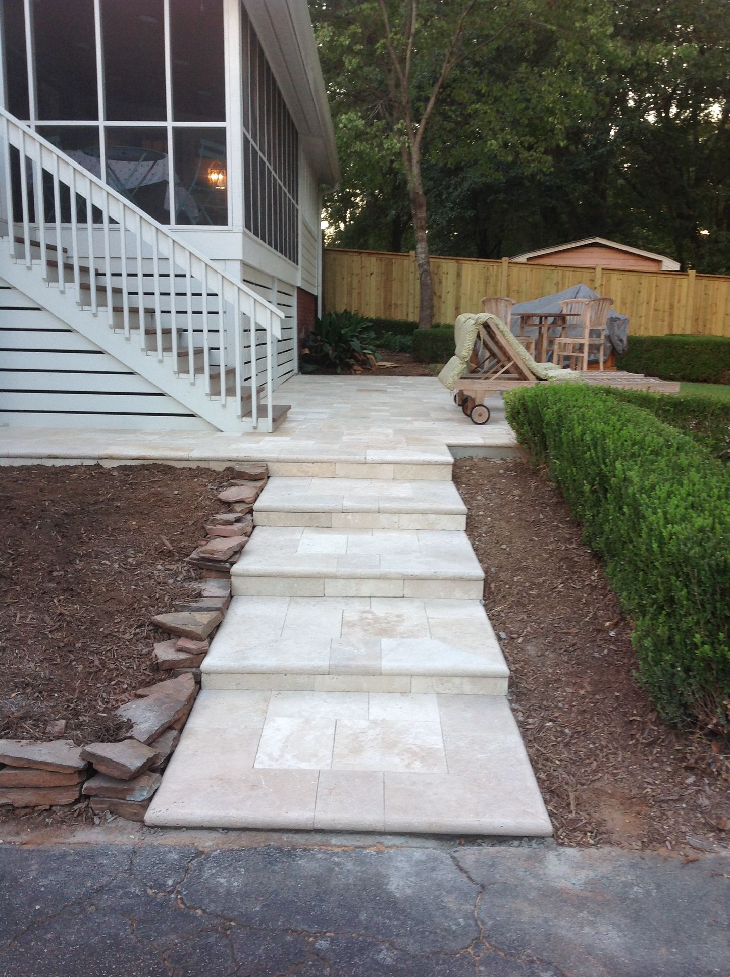 A walkway leading to a screened in porch with stairs