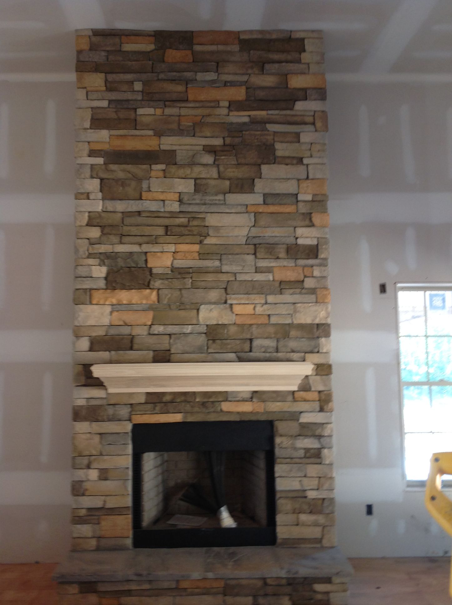 A stone fireplace in a room with a window