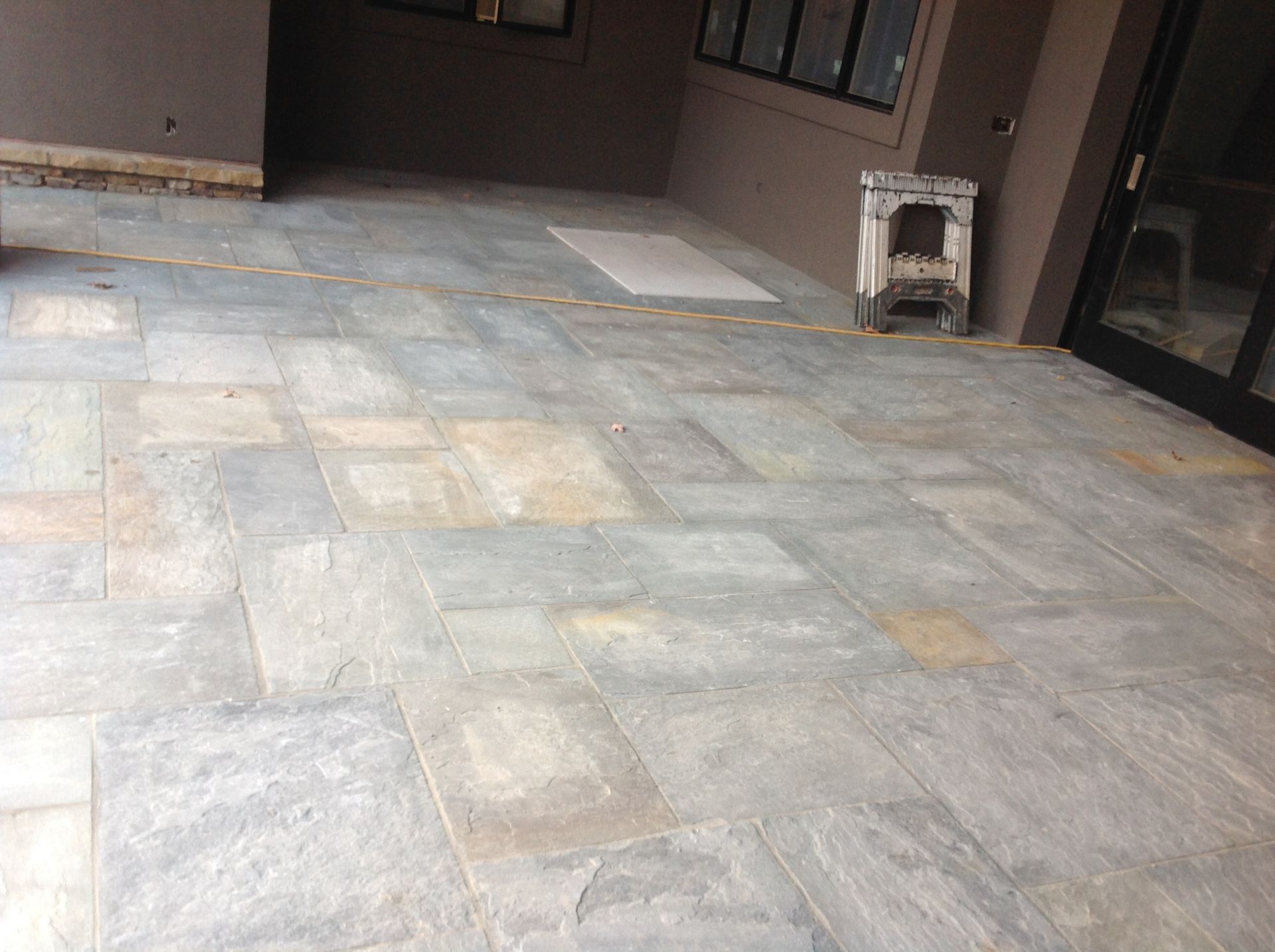 A patio with a lot of tiles on it and a fireplace in the background.