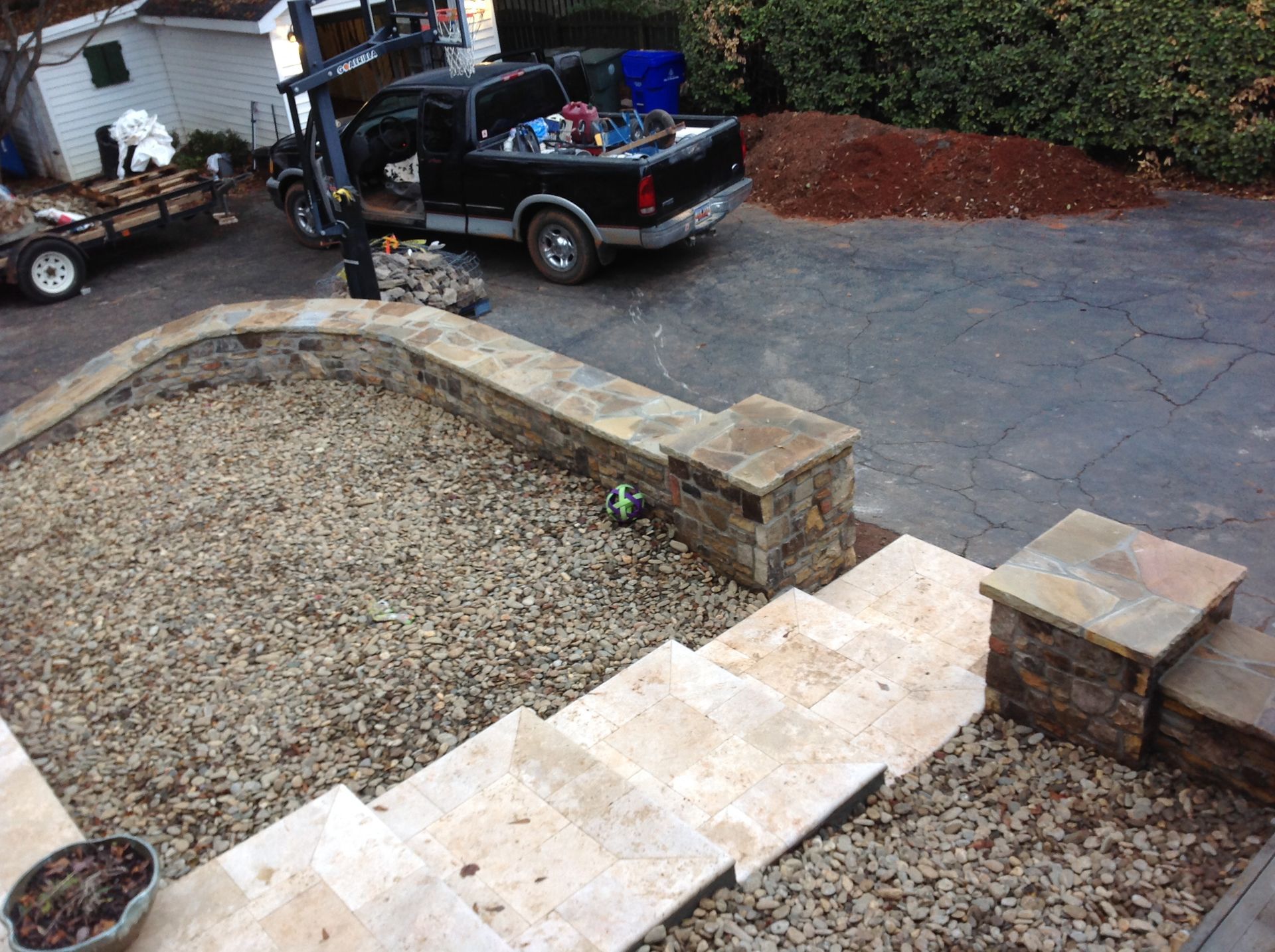 A black truck is parked in a driveway next to stairs.