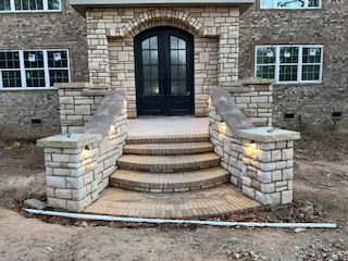 A stone porch with stairs leading up to the front door of a house.
