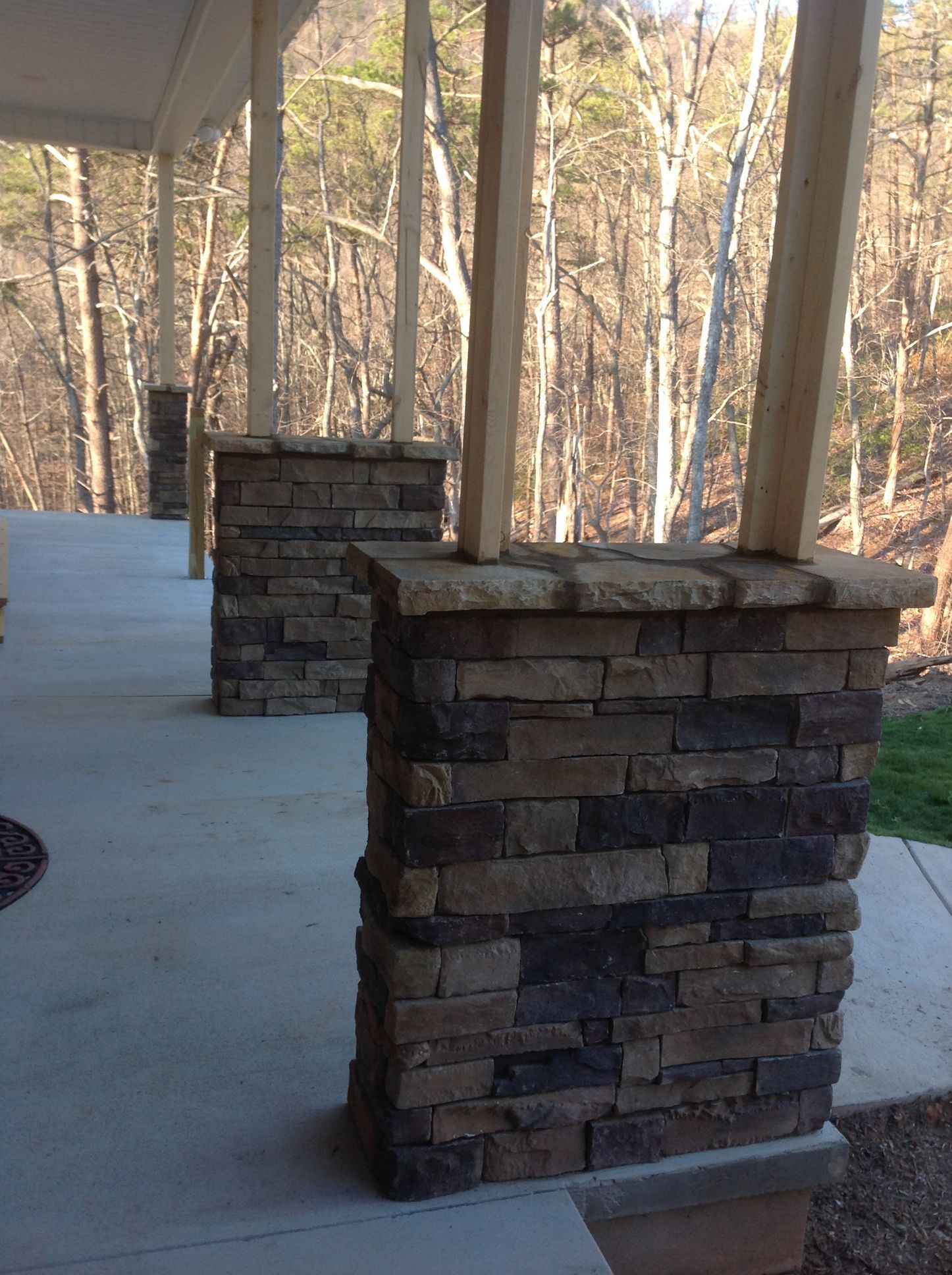 A porch with brick pillars and trees in the background