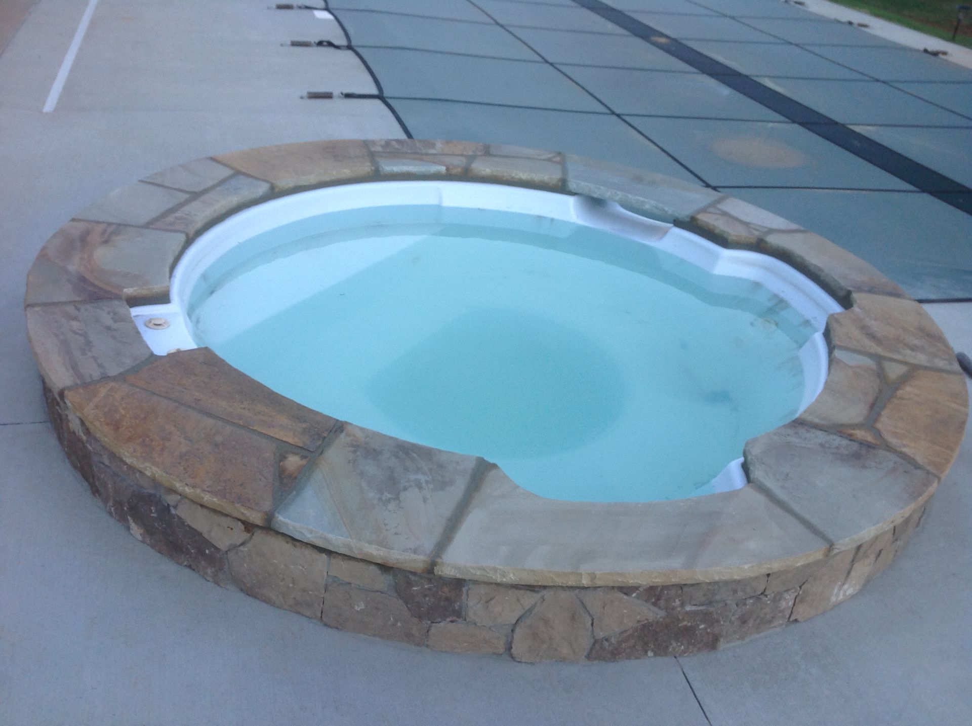 A round pool with a stone border and a cover on it