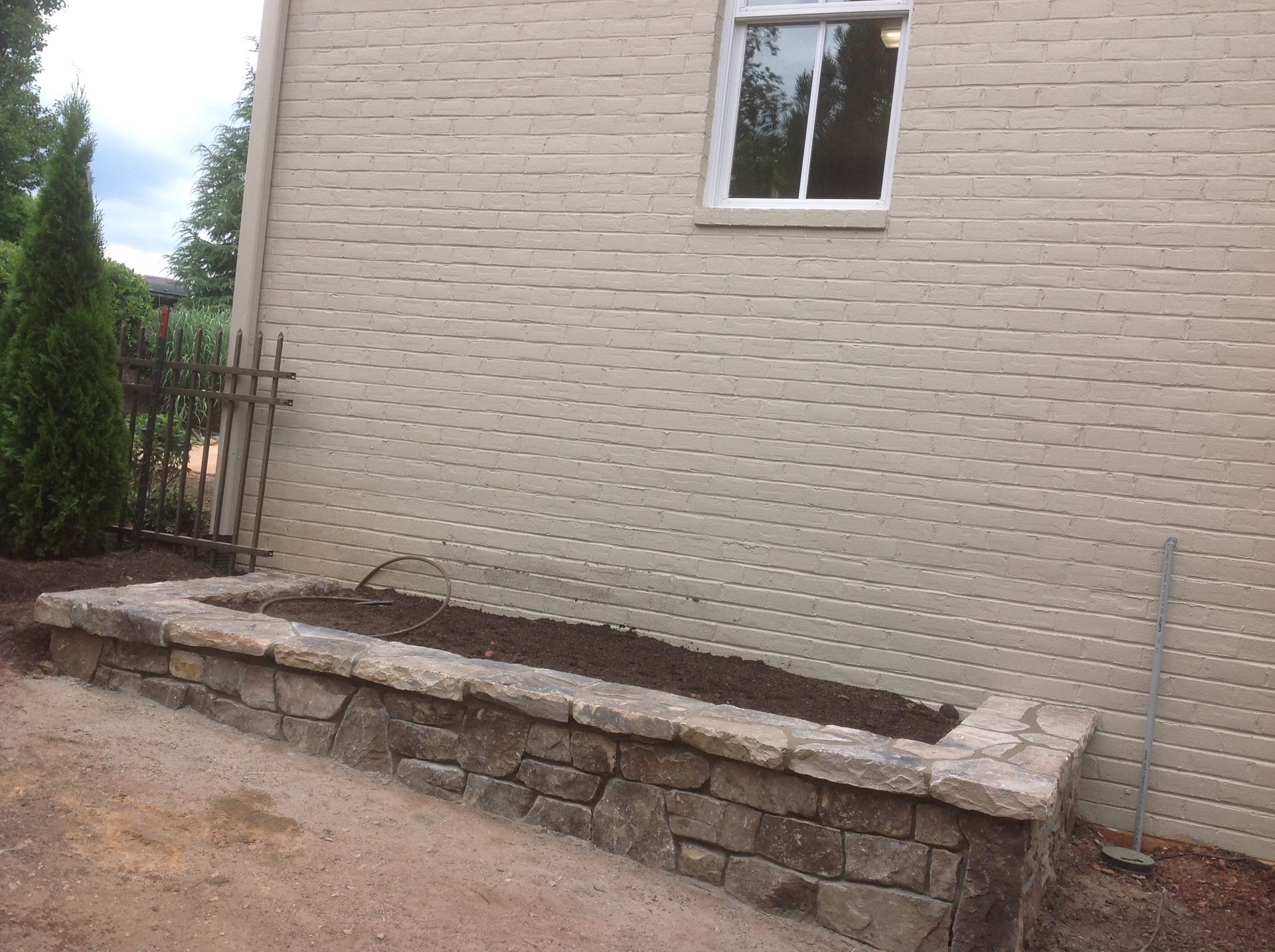 A stone wall is being built in front of a brick building.