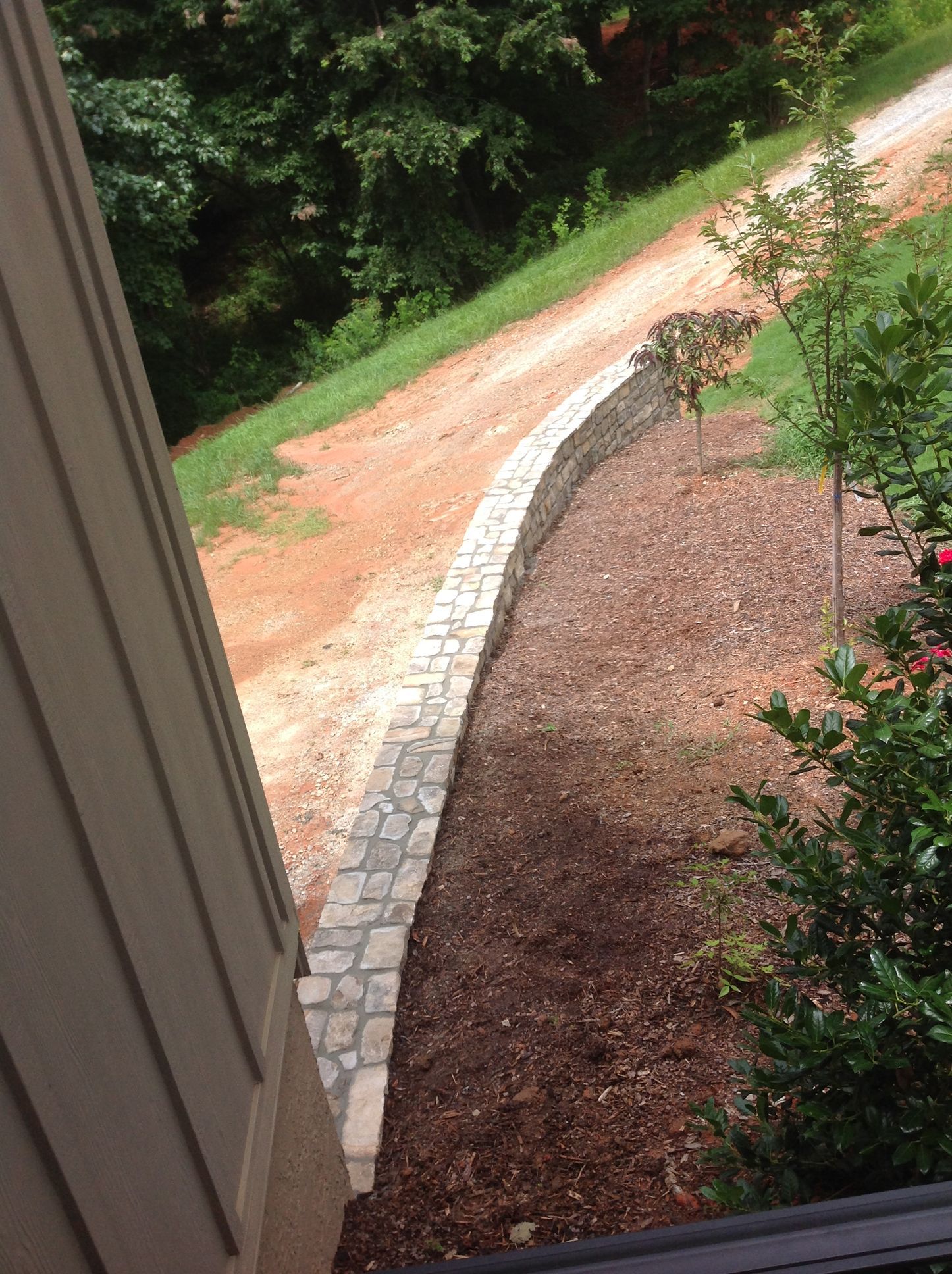 A stone walkway leading to a dirt road next to a house.