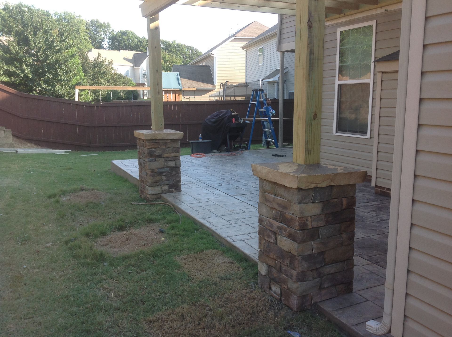 The backyard of a house with a pergola and stone pillars