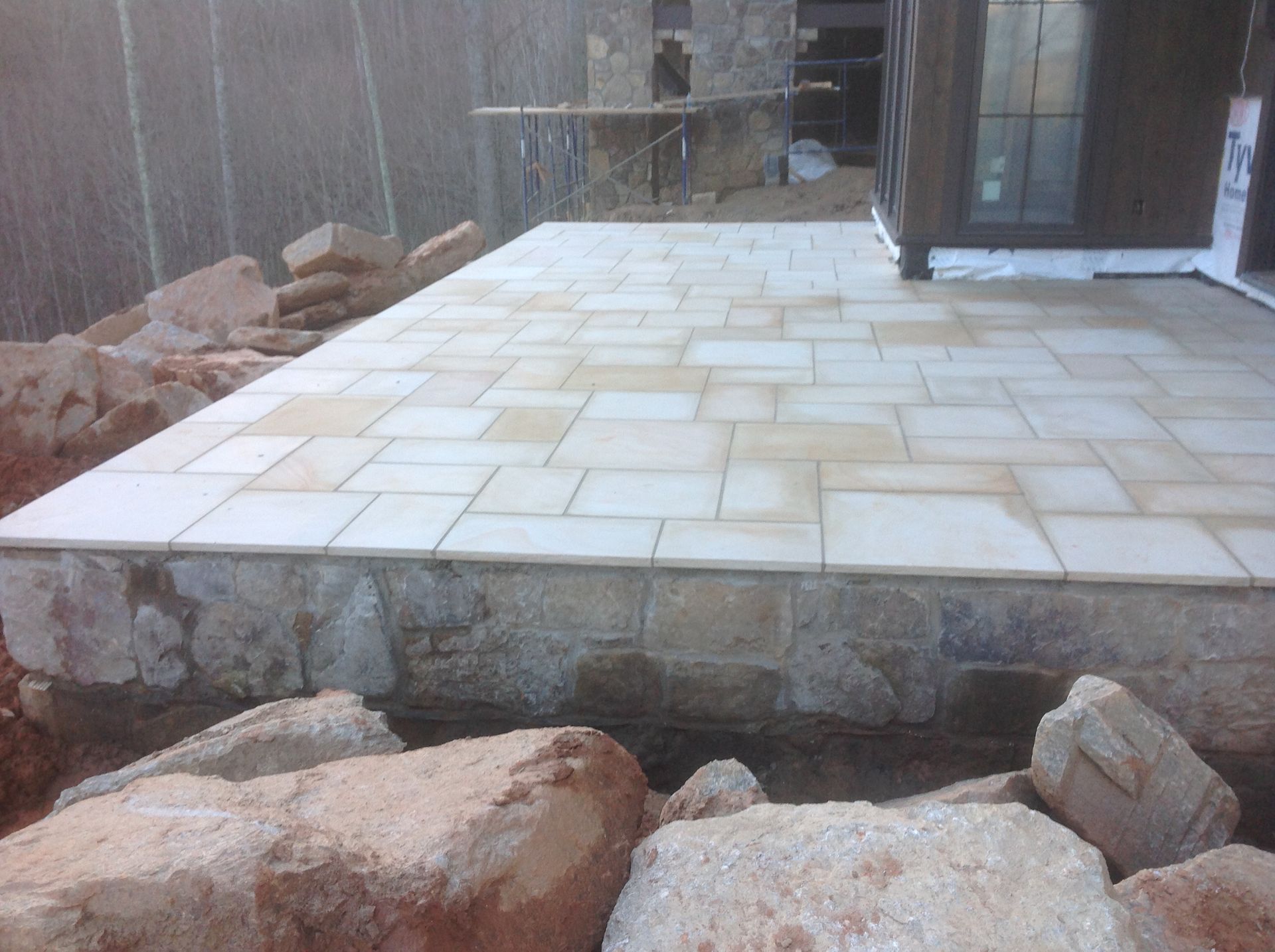 A stone patio is being built in front of a house.
