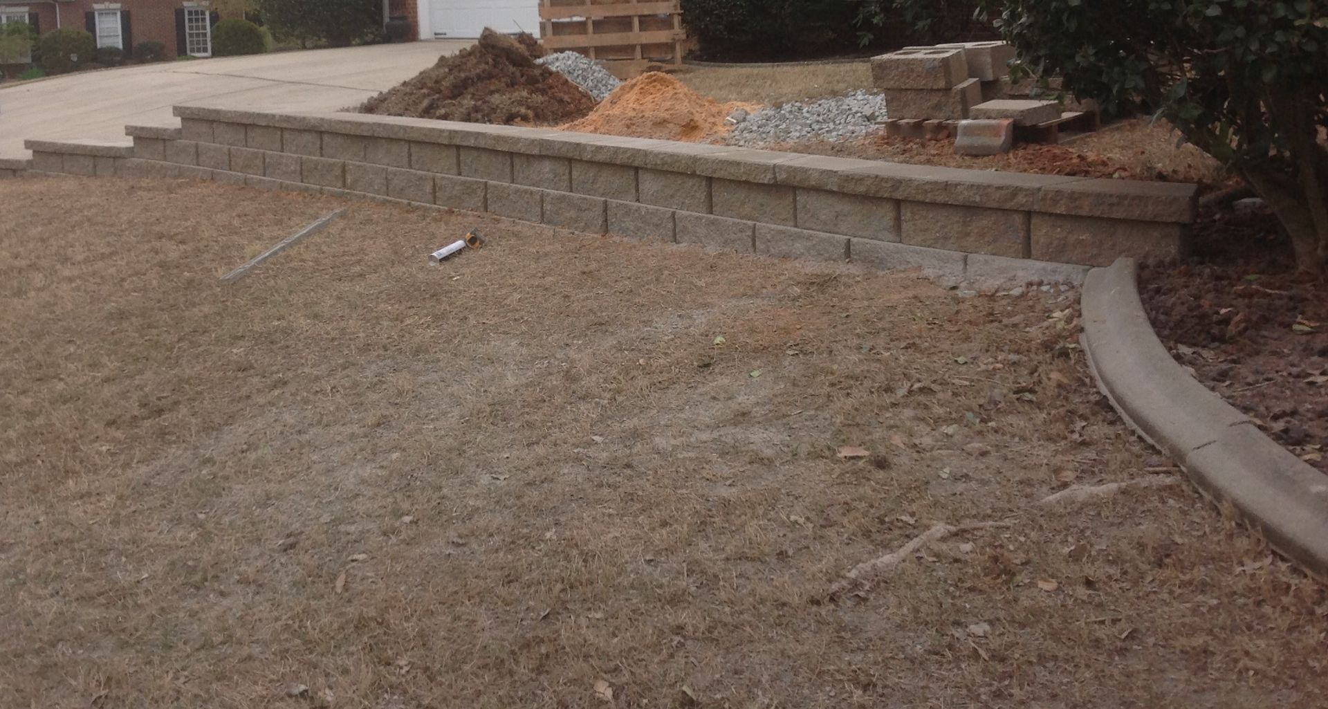 A brick wall is being built in the backyard of a house.