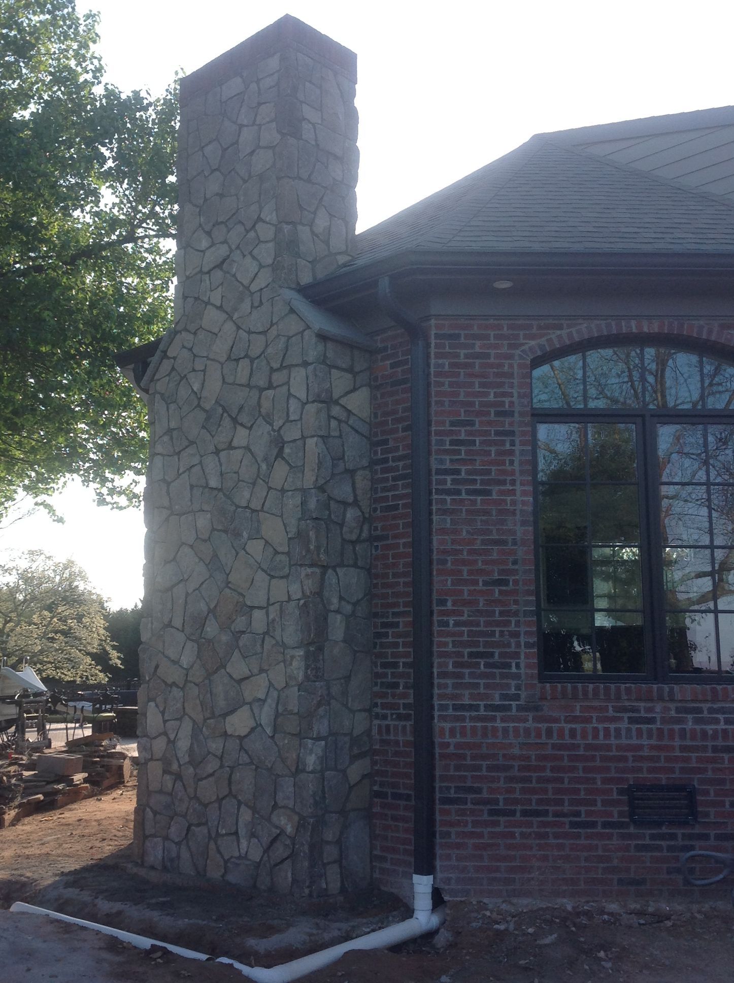 A large stone chimney on the side of a brick building