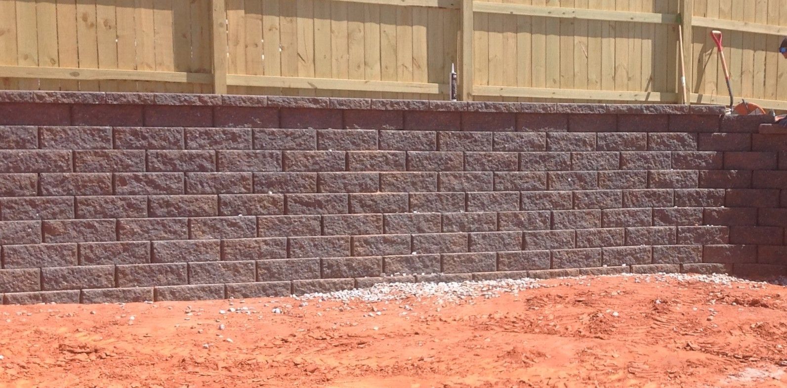 A brick wall is being built next to a wooden fence.