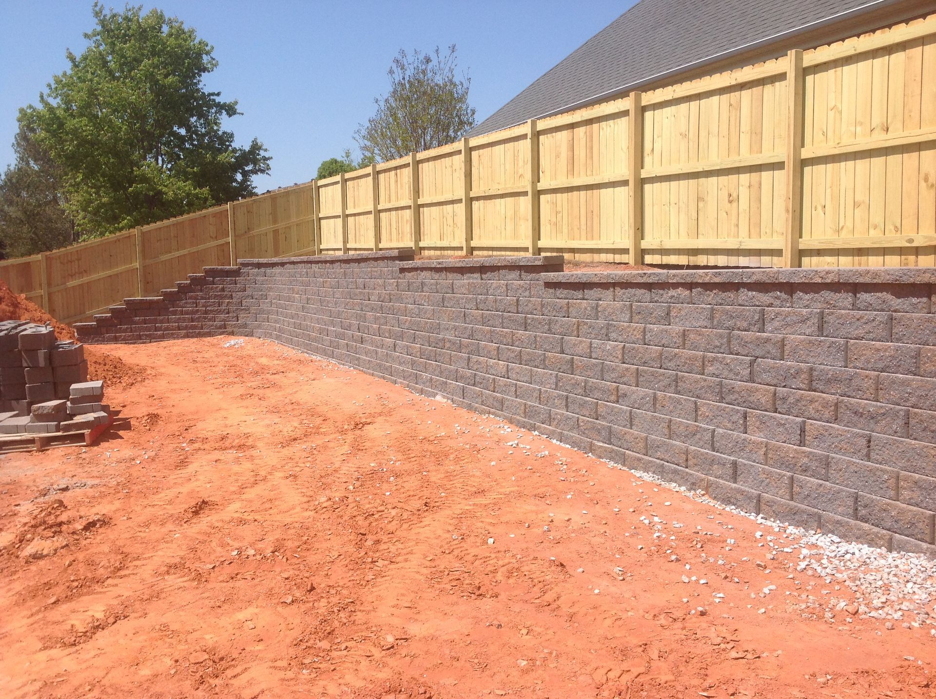 A brick wall with a wooden fence behind it