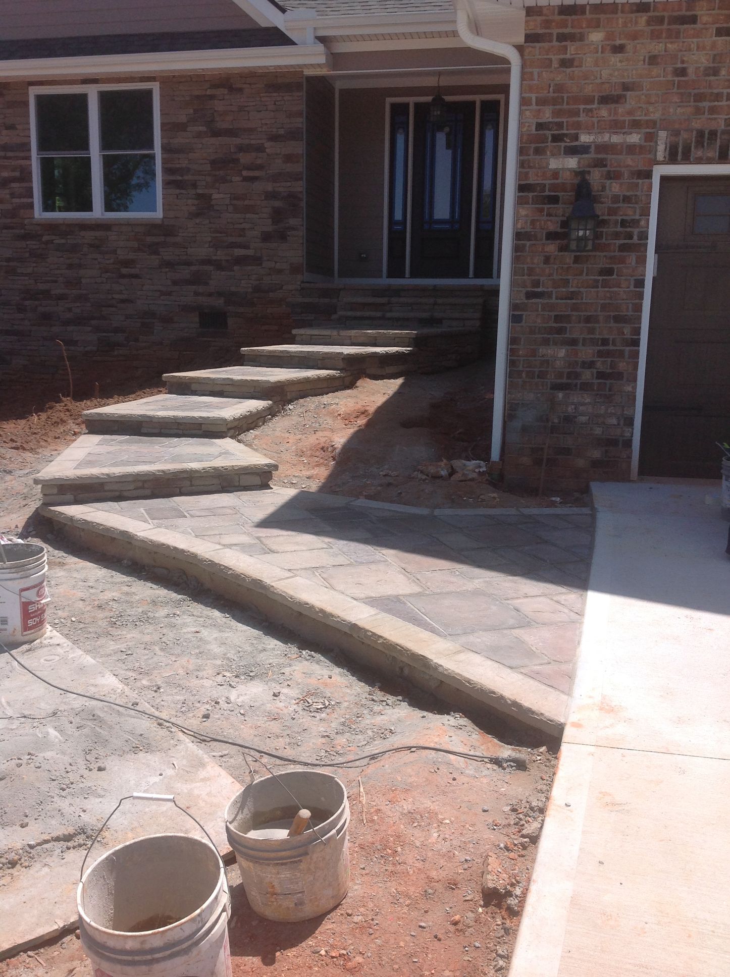 Two buckets are sitting in front of a brick house.