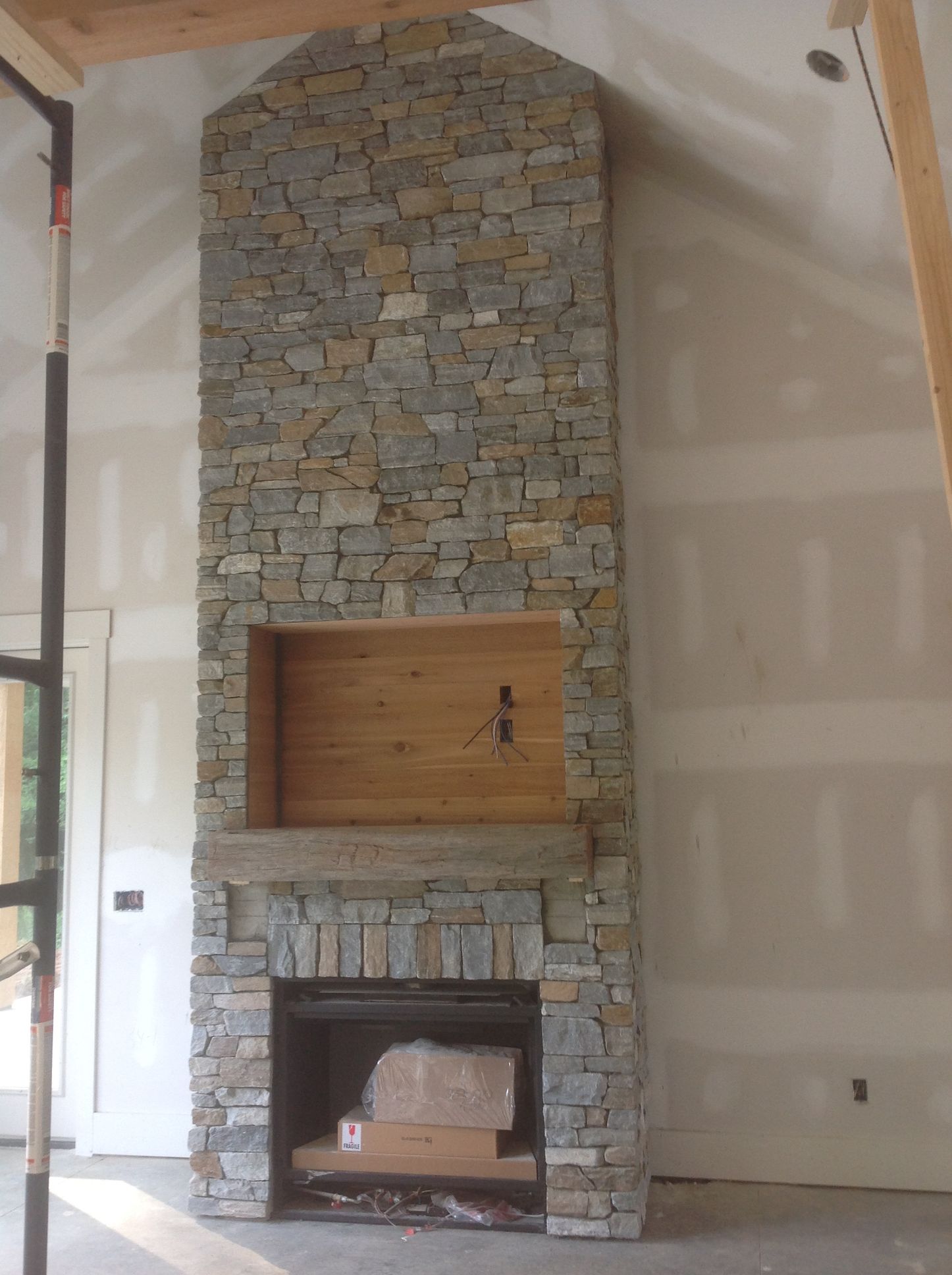A stone fireplace with a wooden mantle