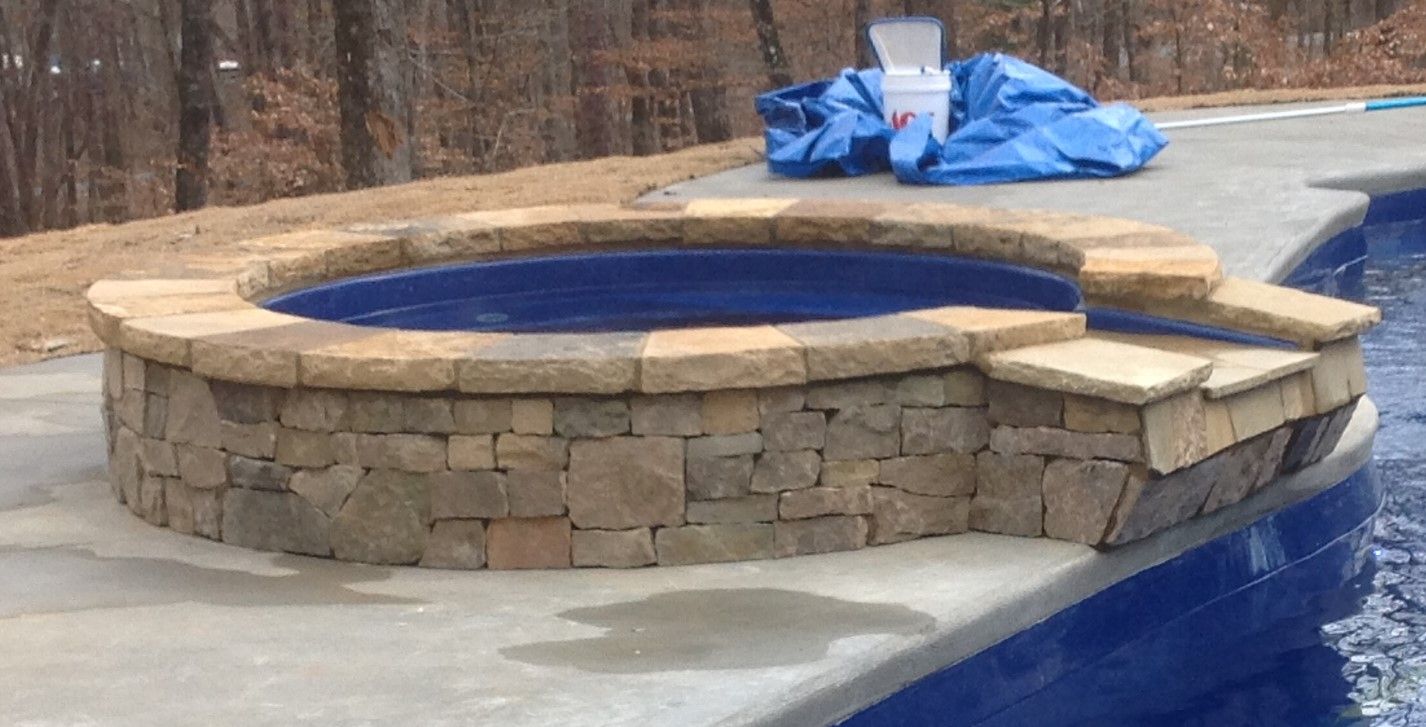 A hot tub is sitting next to a swimming pool.