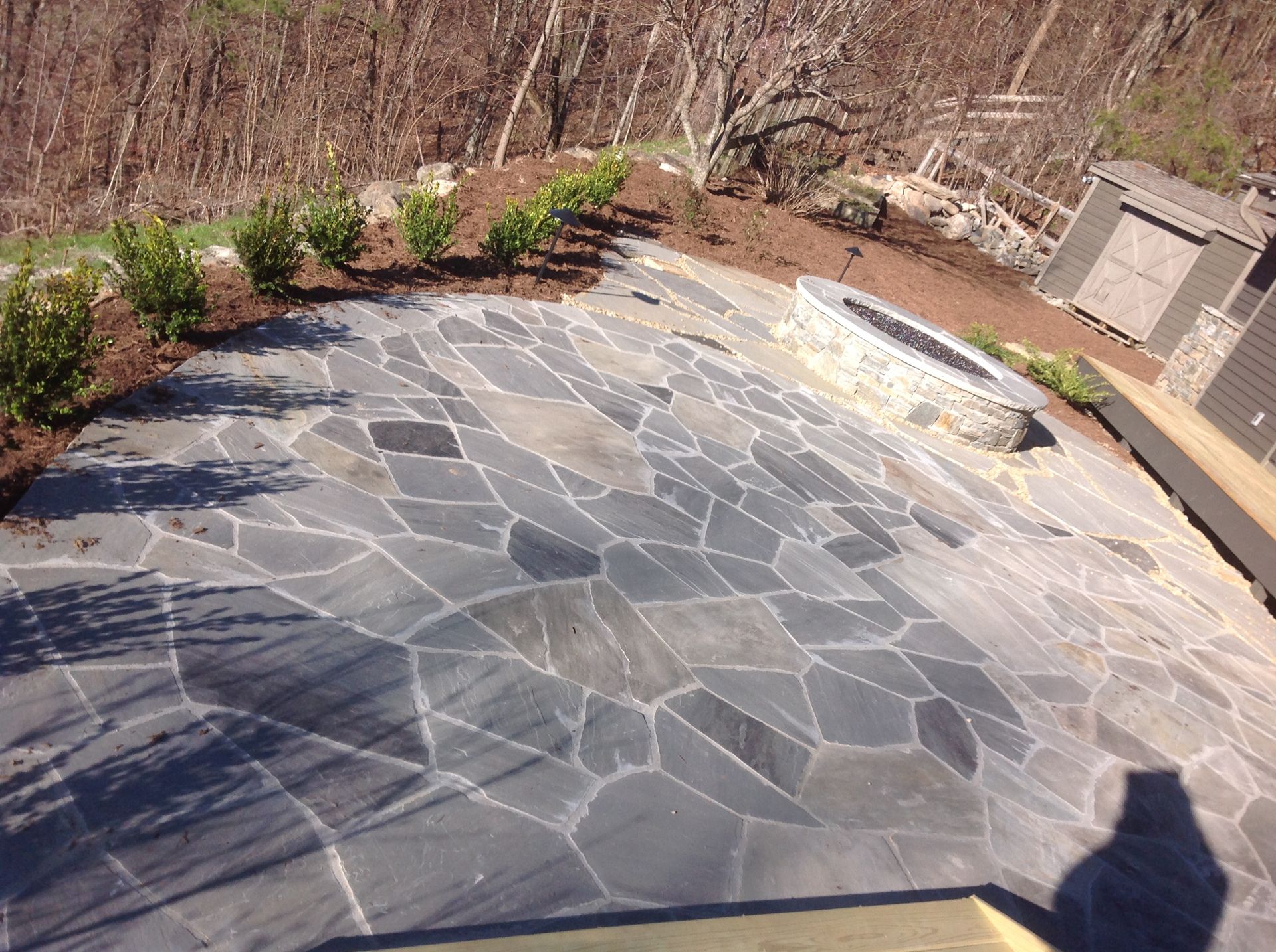 A stone patio with a fire pit in the middle of it