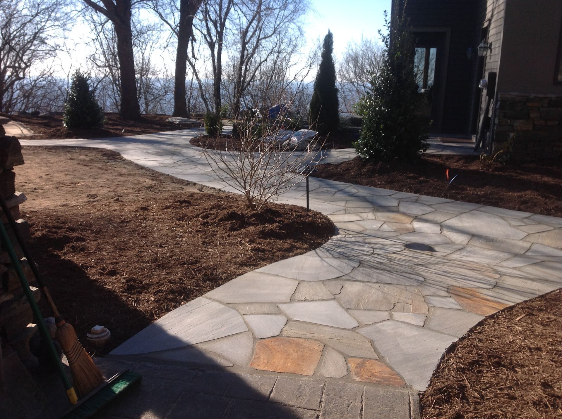 A stone walkway leading to a house with trees in the background