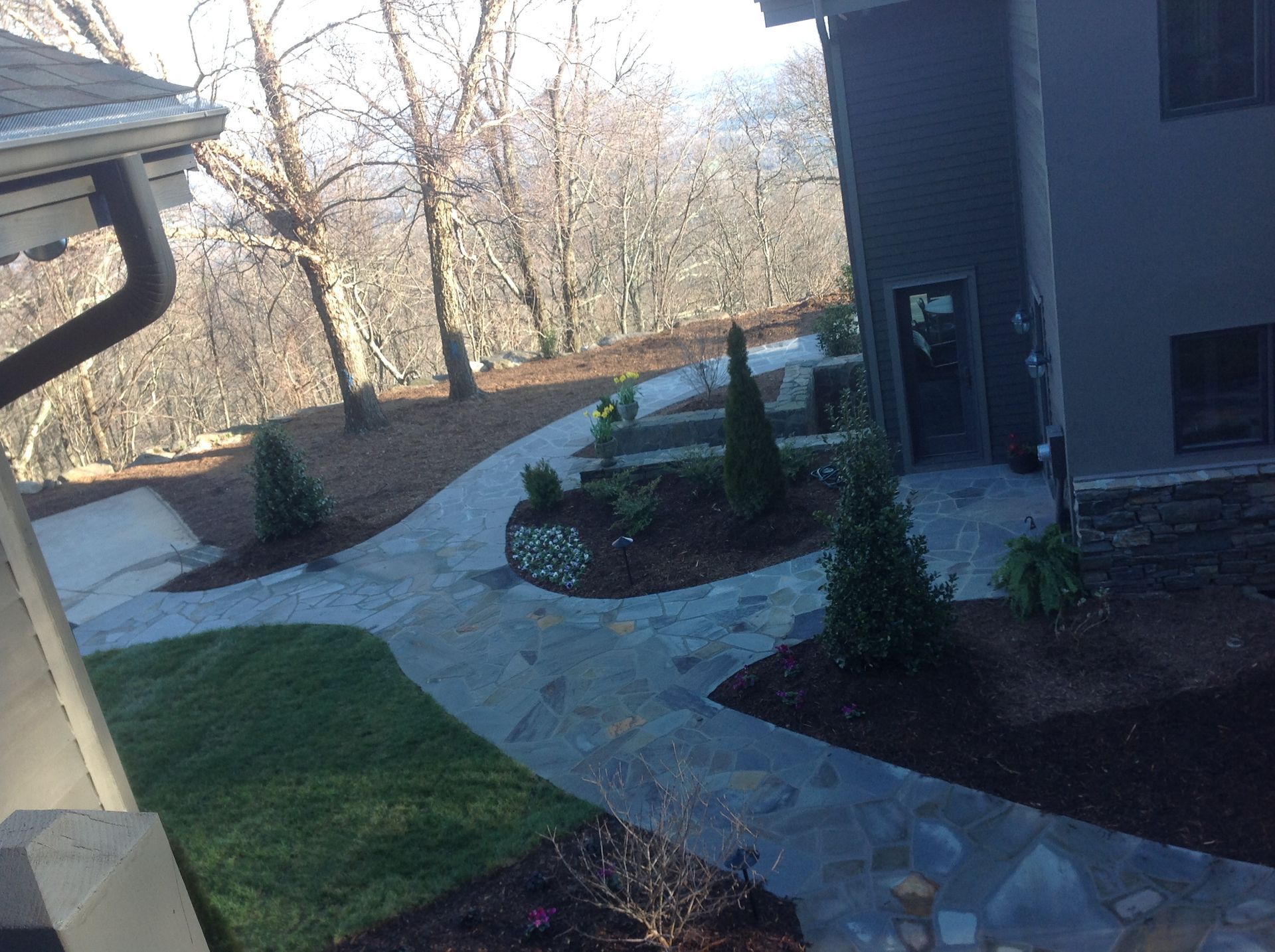 A stone walkway leading to a house with trees in the background