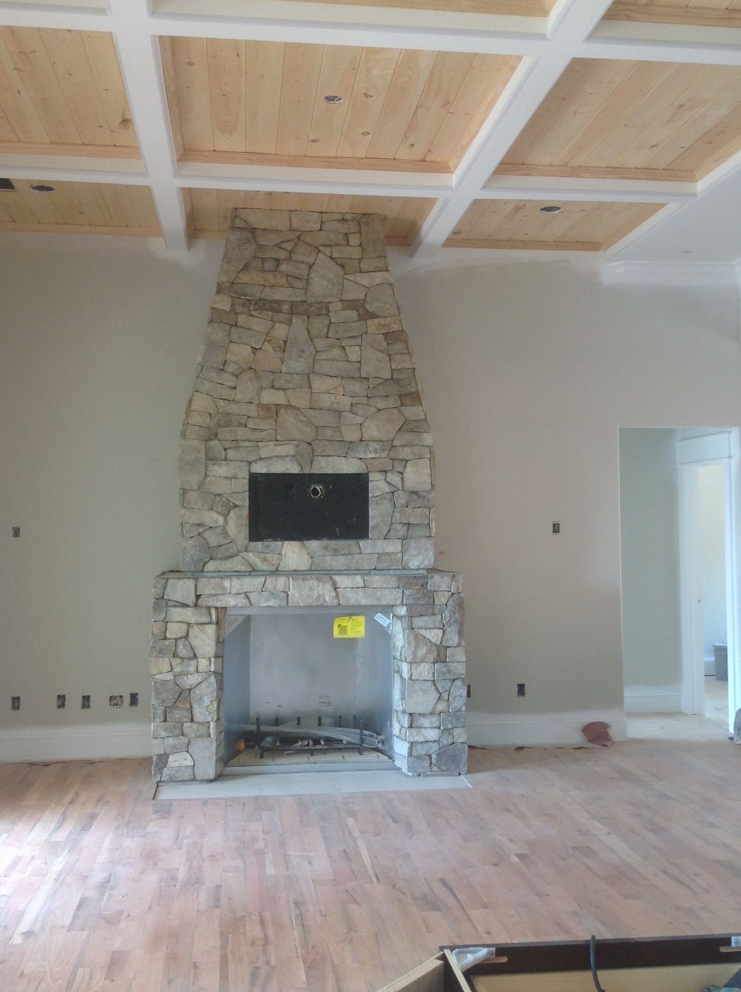 A living room with a stone fireplace and a wooden ceiling