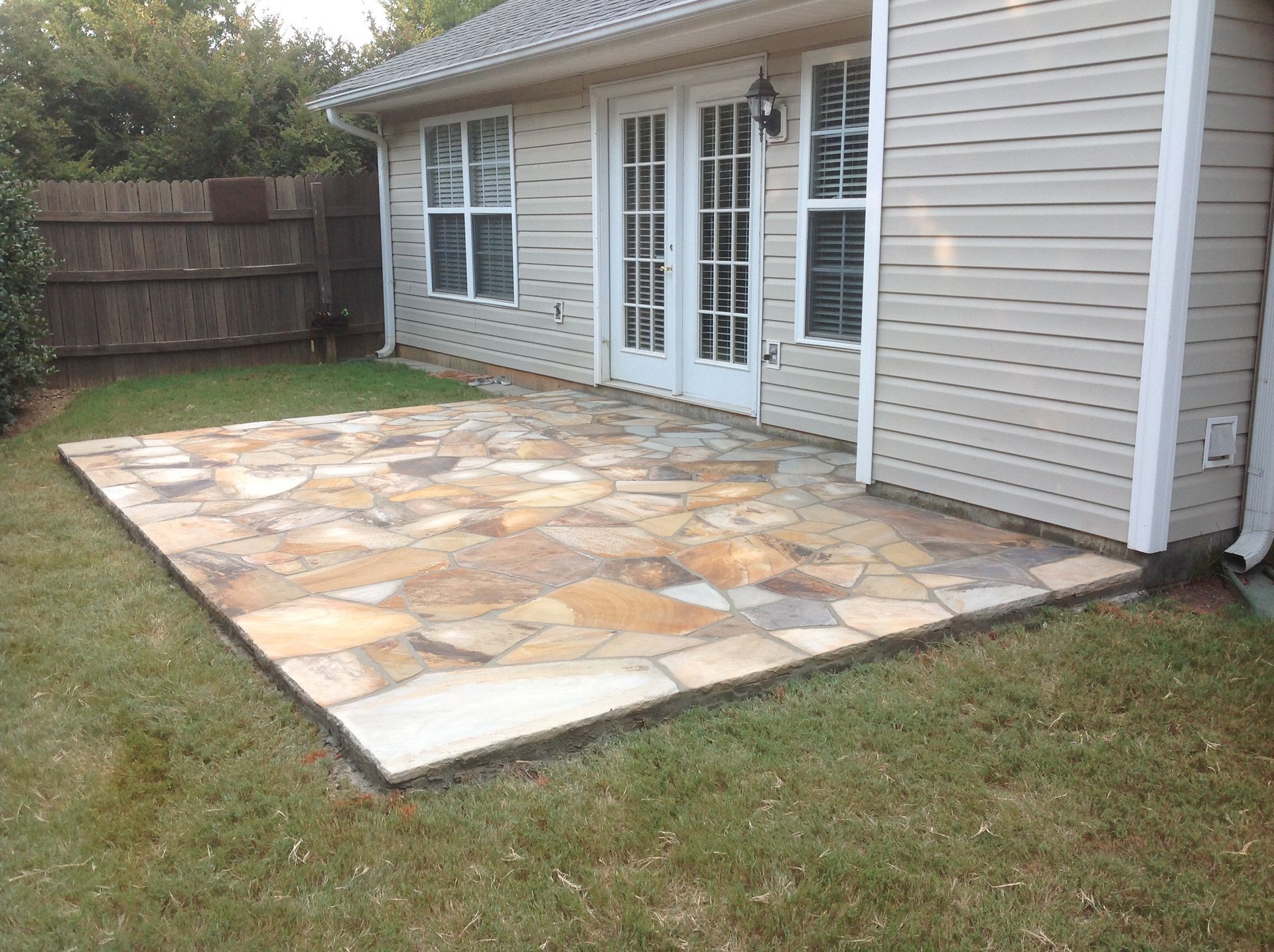A house with a stone patio in front of it.