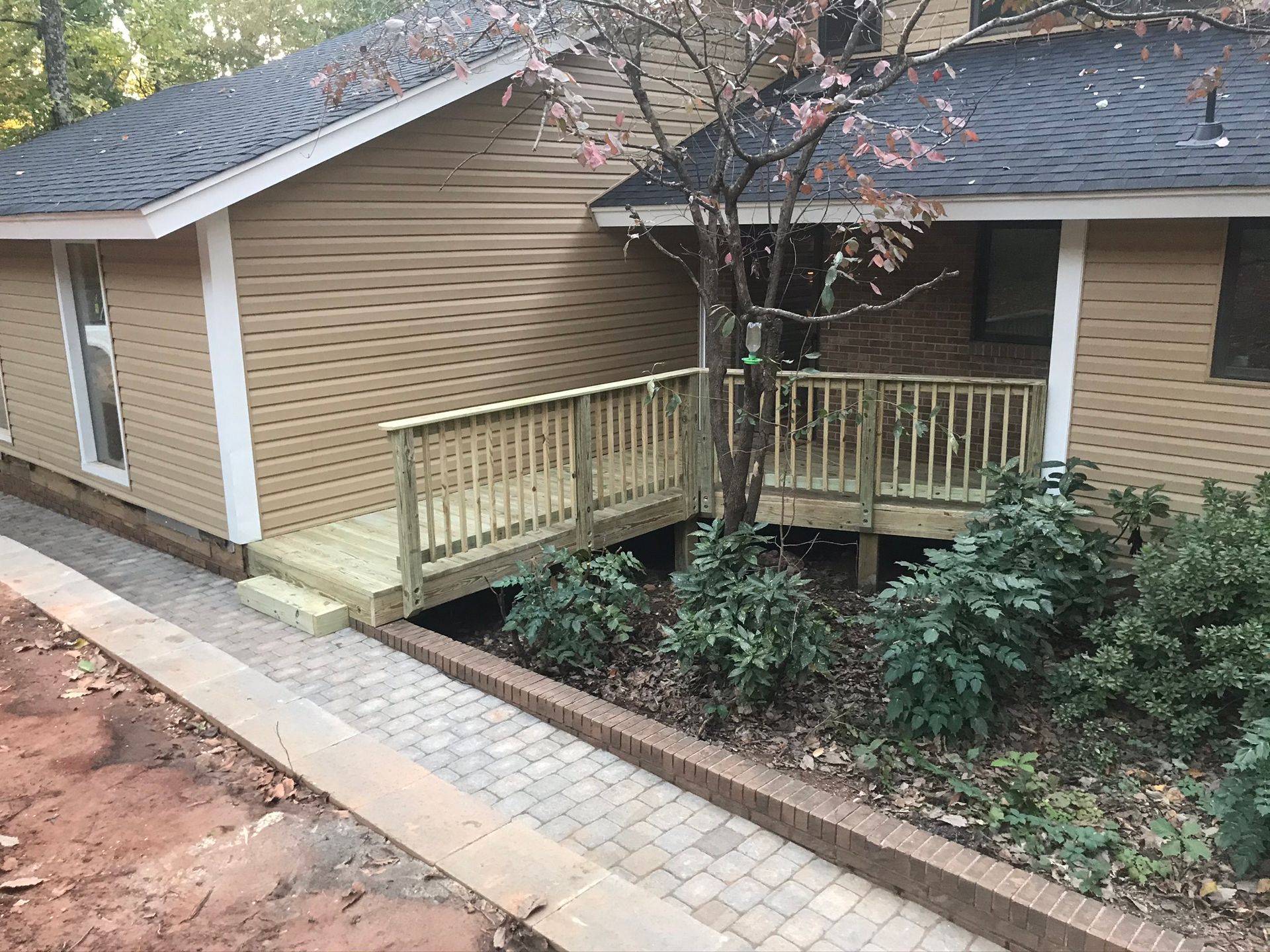 A house with a wooden deck and a walkway leading to it.