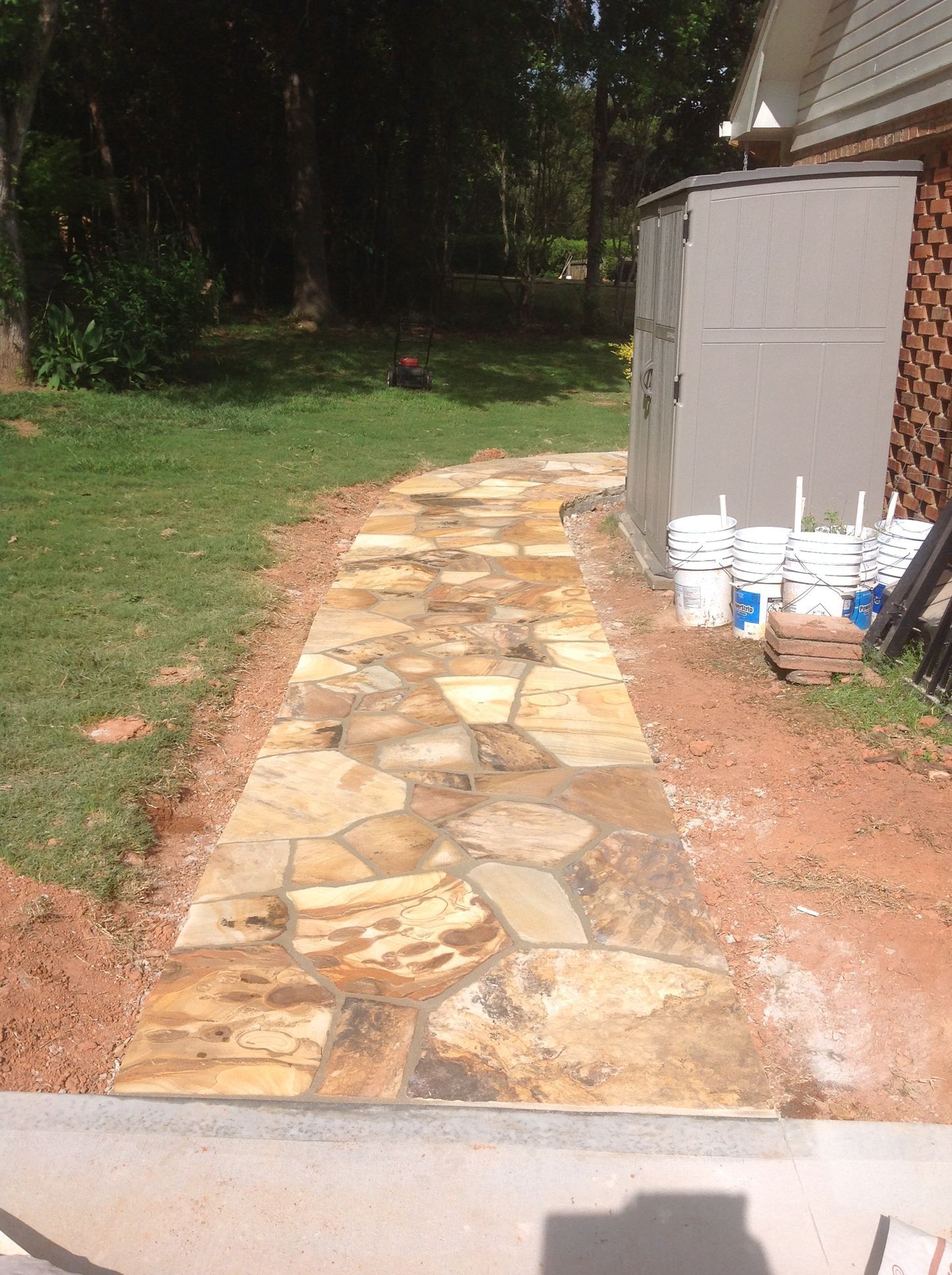A stone walkway is being built in the backyard of a house.