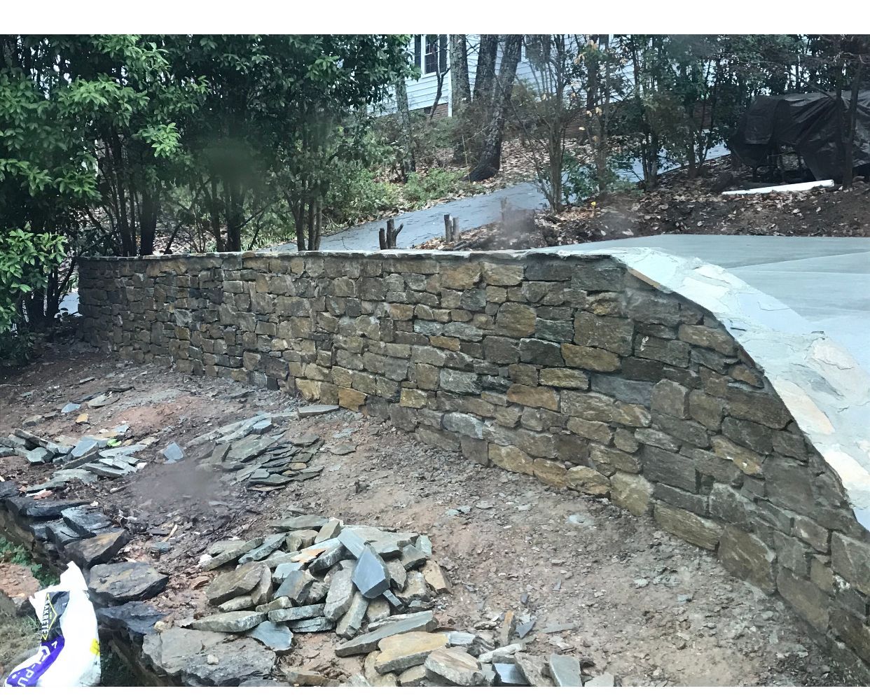 A stone wall is being built next to a road.
