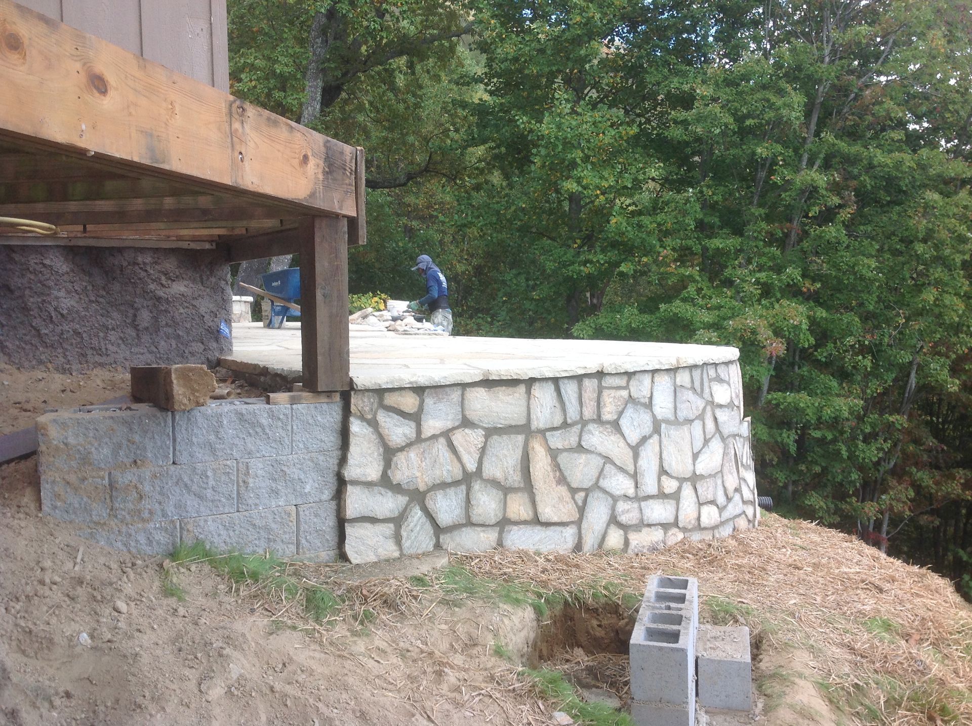 A stone wall is being built next to a wooden deck.
