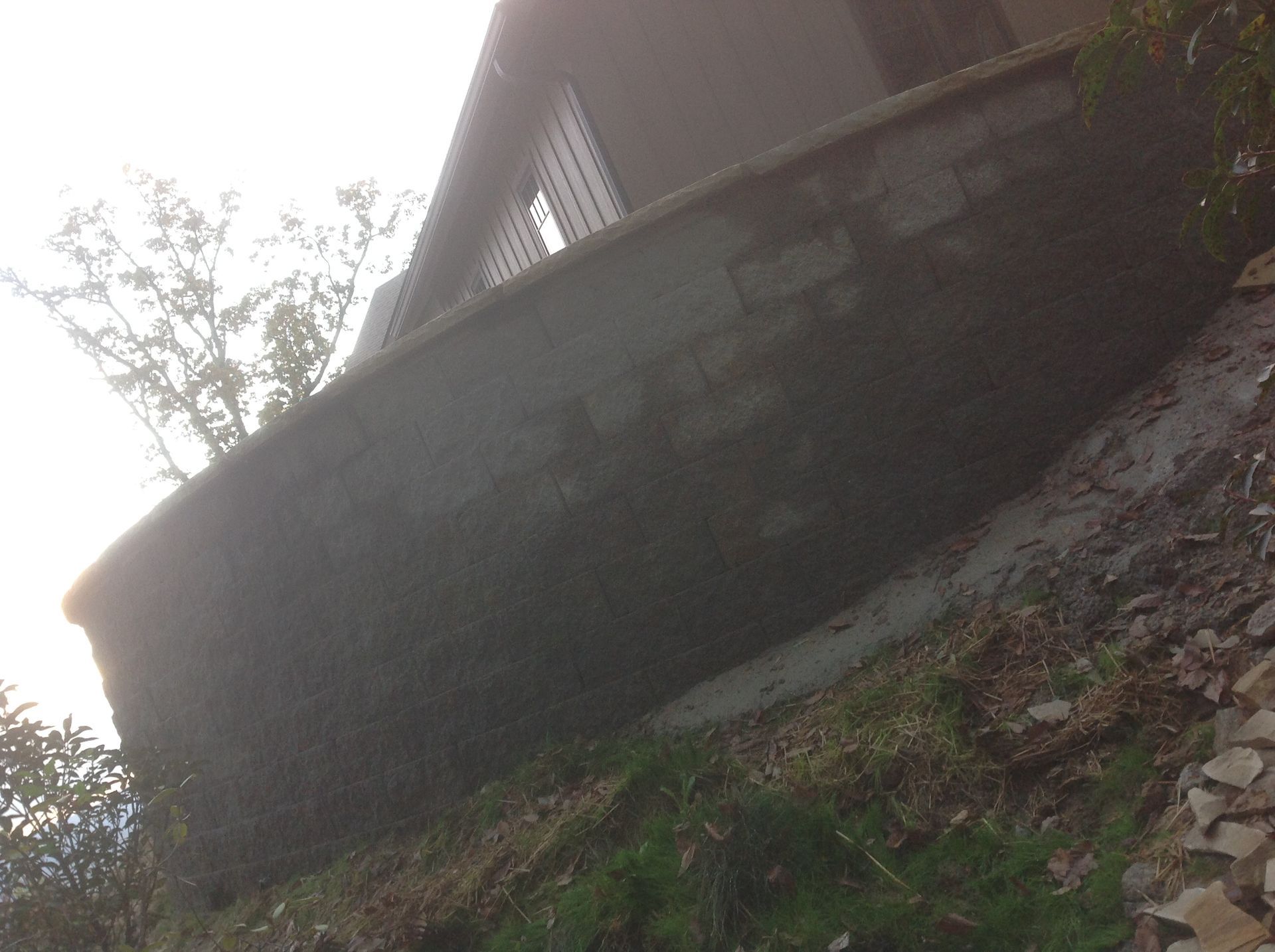 A black building is sitting on top of a grassy hill.