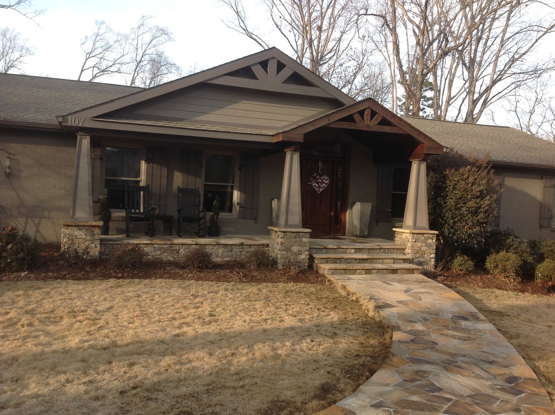 A house with a porch and a stone walkway leading to it