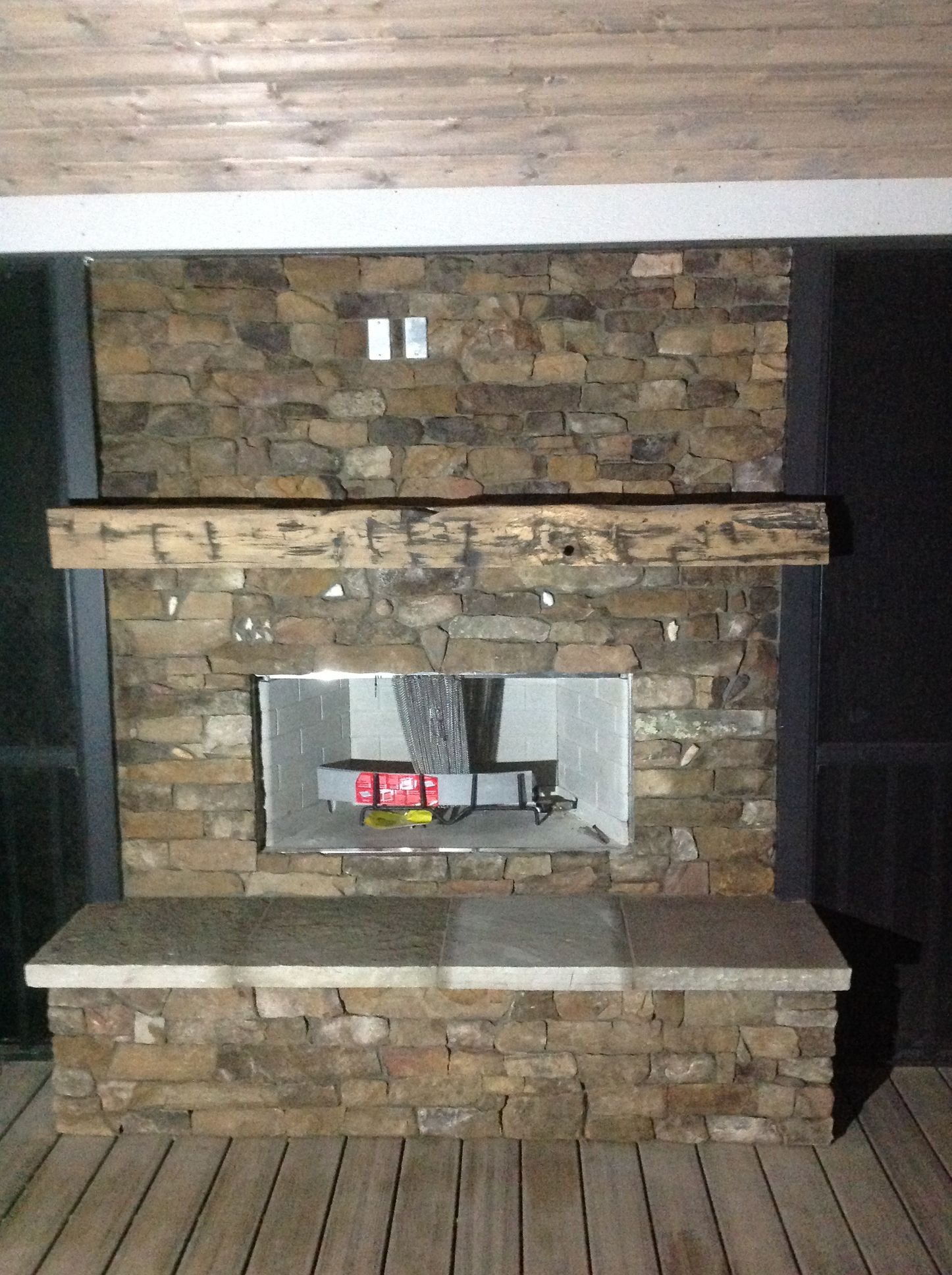 A stone fireplace with a wooden mantle and a wooden floor