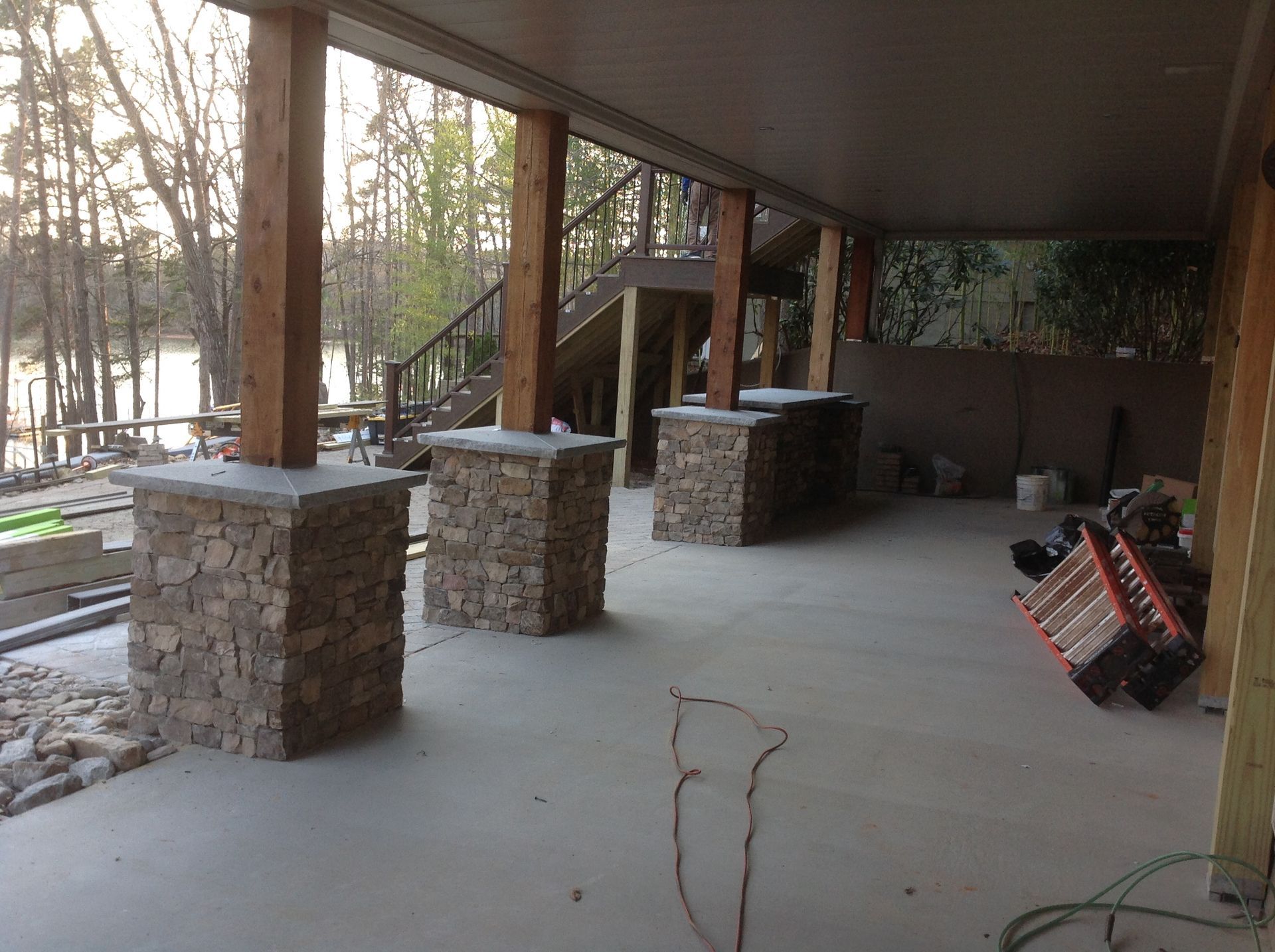 A patio with stone pillars and a ladder on the ground