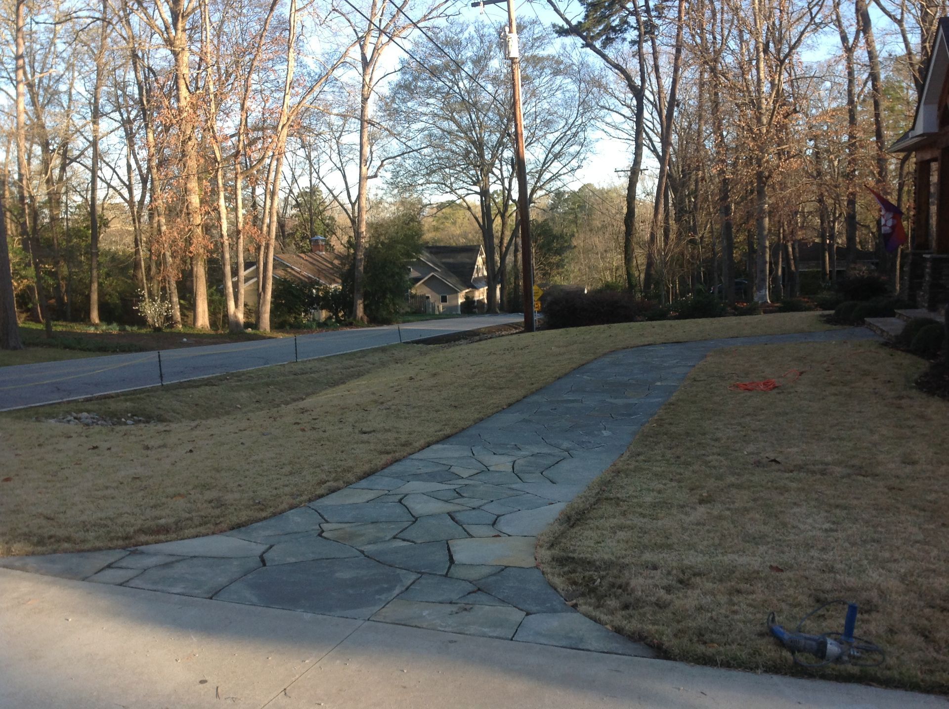 A stone walkway leading to a house with trees in the background