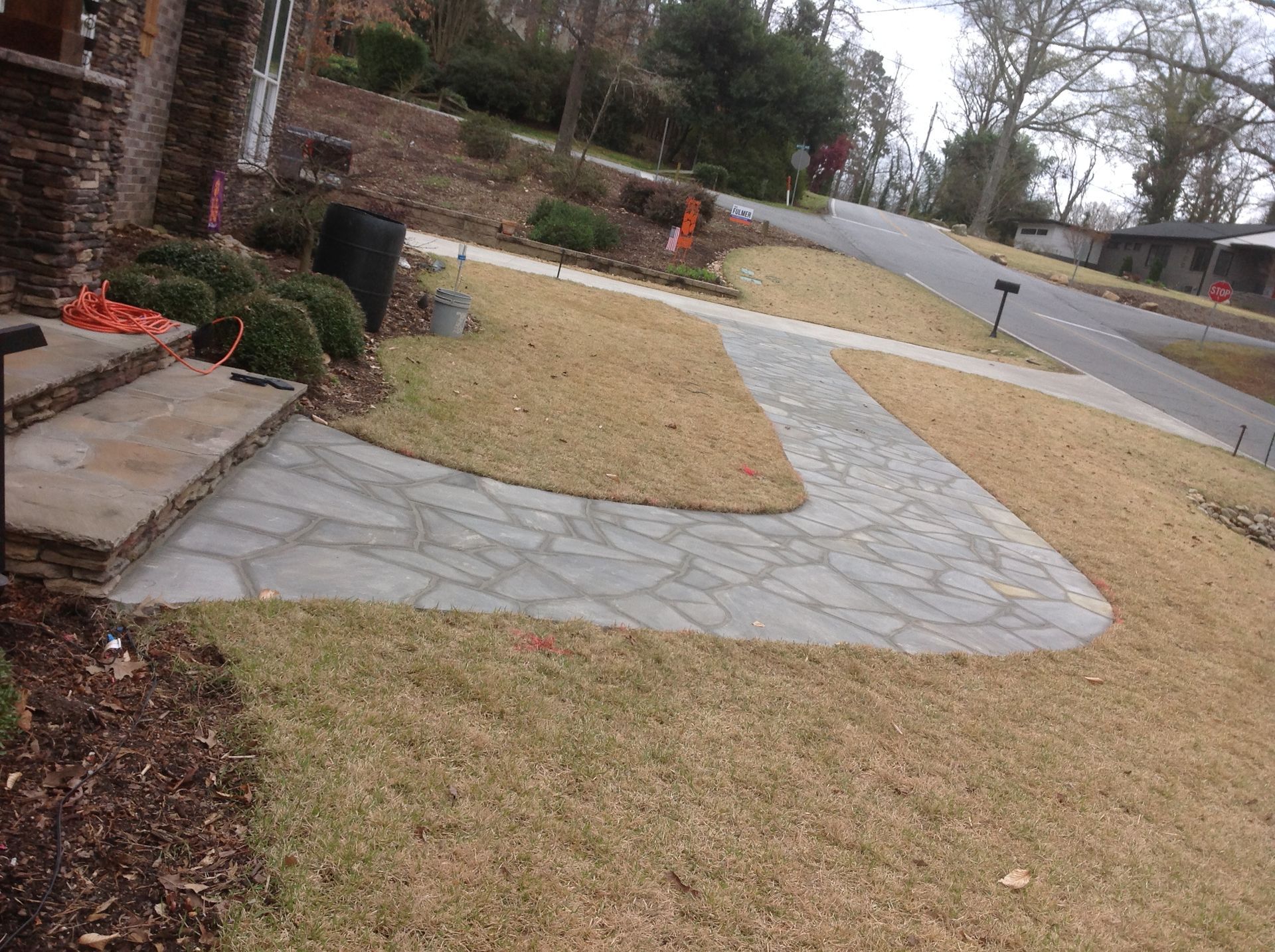 A stone walkway is being built in the front yard of a house.