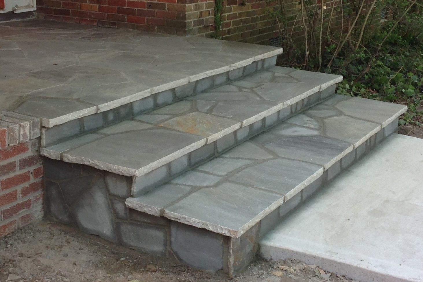 A set of stone steps leading up to a brick porch.