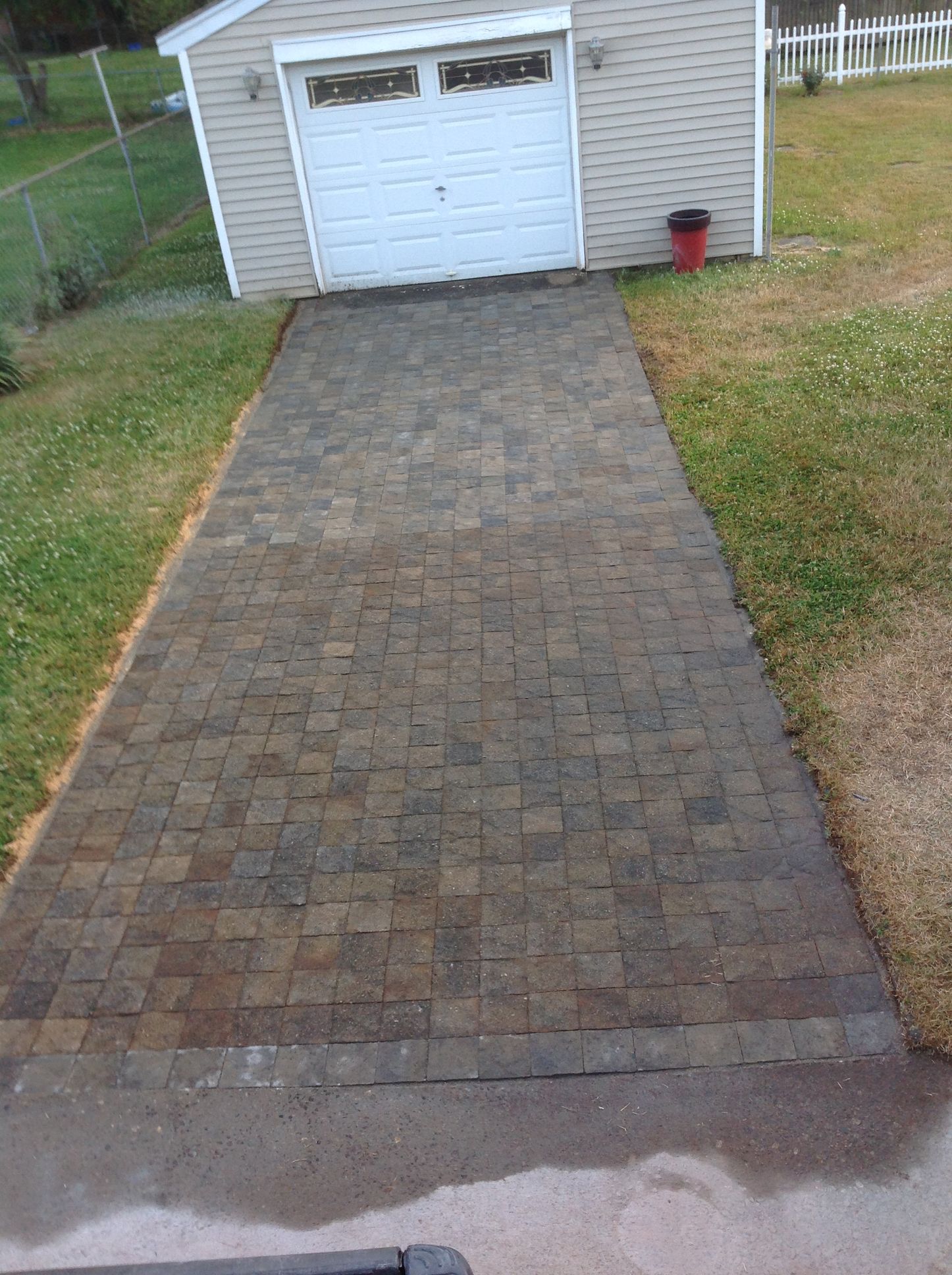 A brick driveway leading to a garage with a white garage door.