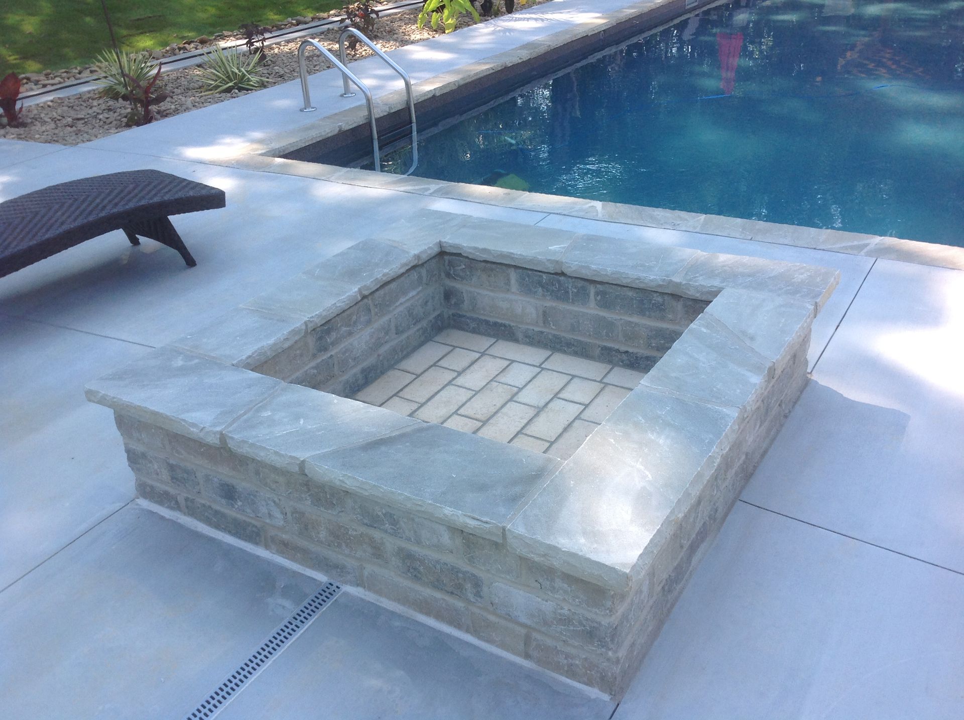 A fire pit is sitting next to a swimming pool.