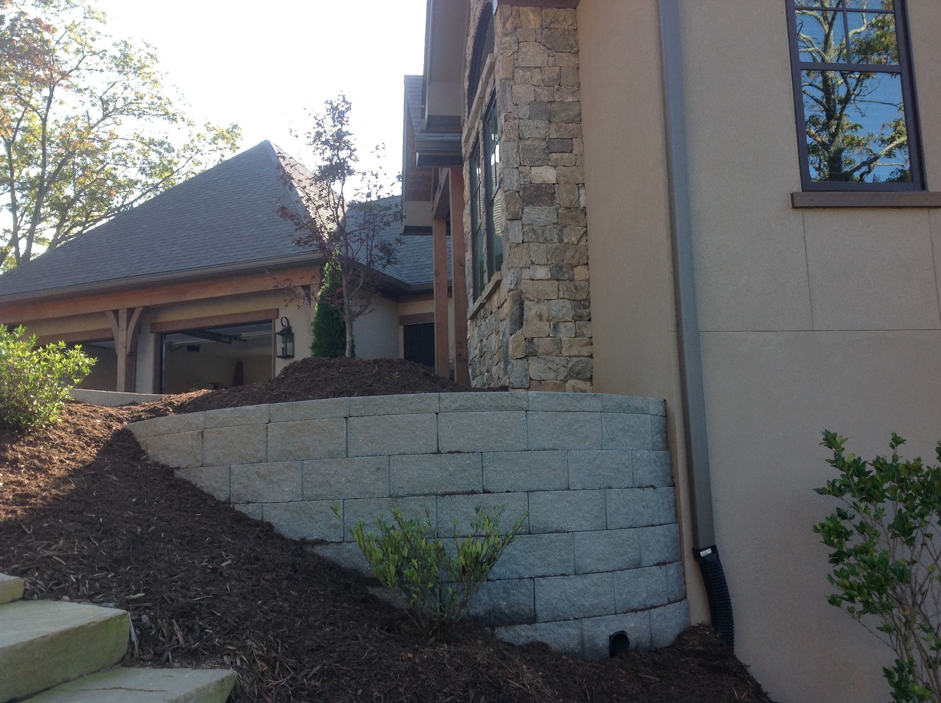 The side of a house with a stone wall and stairs