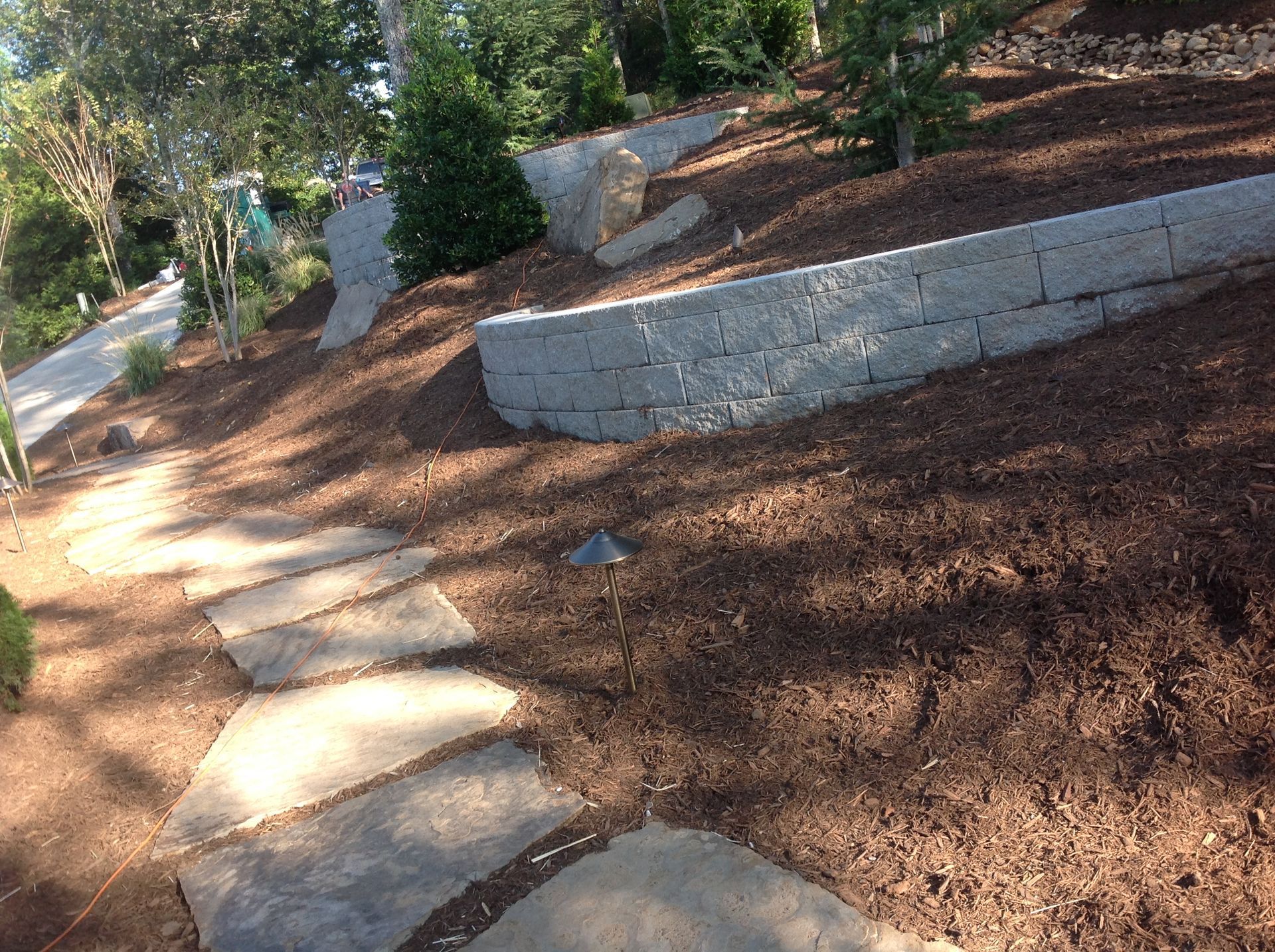 A stone walkway going up a hill next to a brick wall.