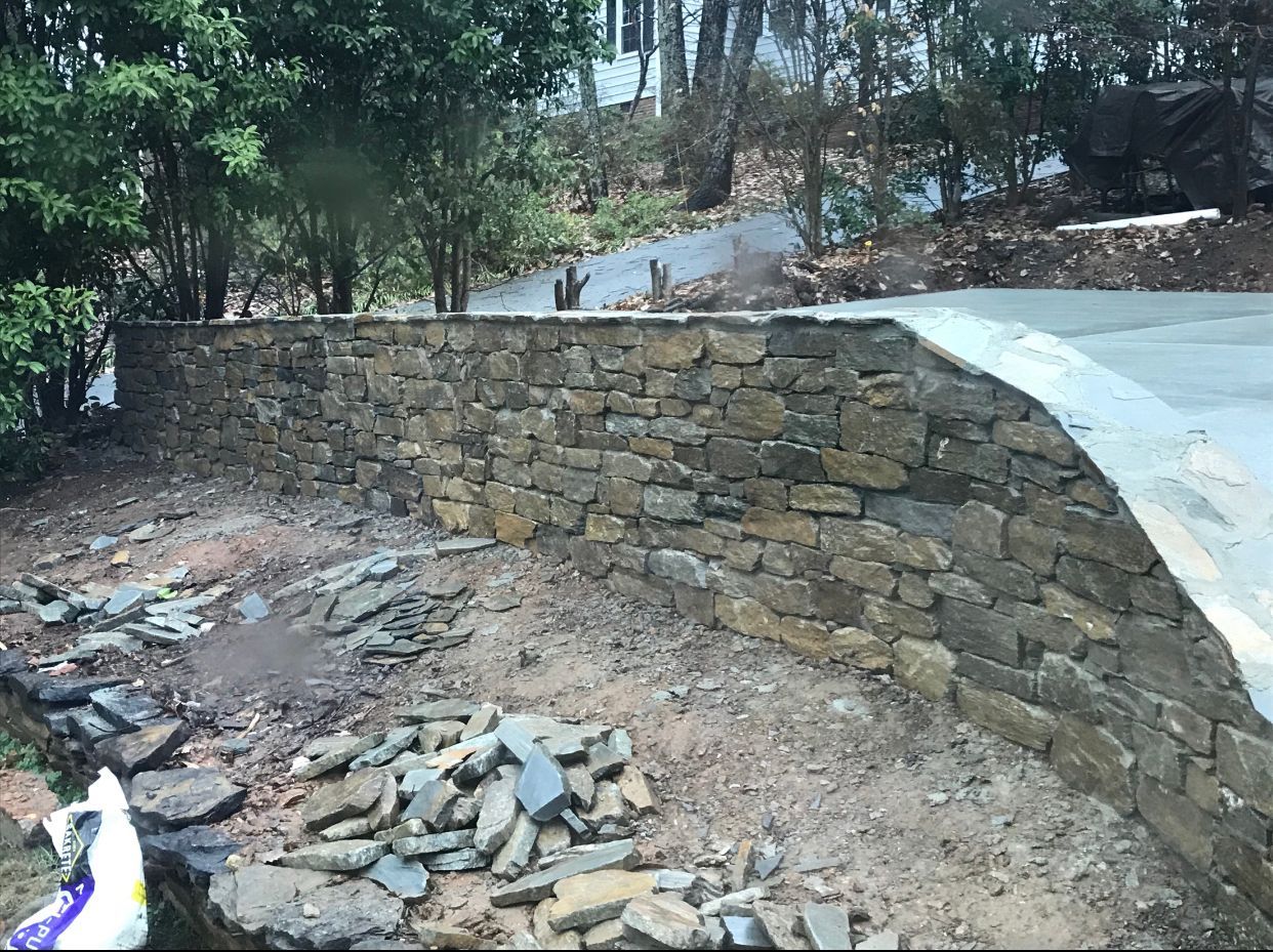 A stone wall is being built next to a road.
