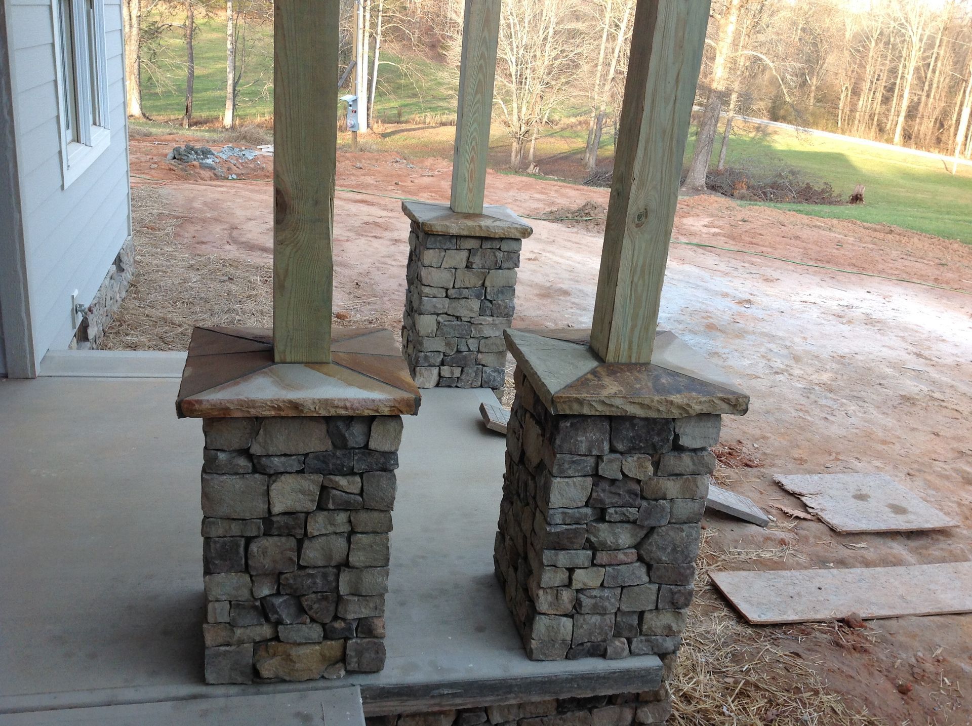 A porch with stone pillars and wooden posts.